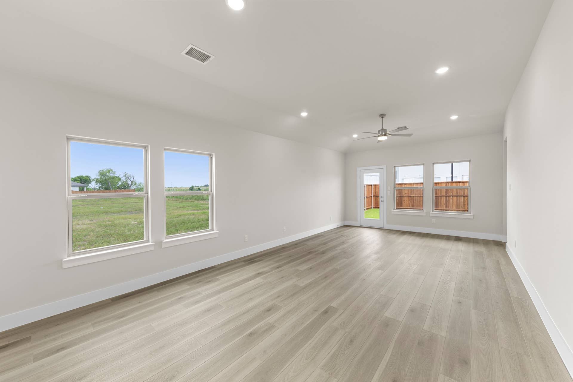 Spacious dining room with large windows and hardwood flooring.