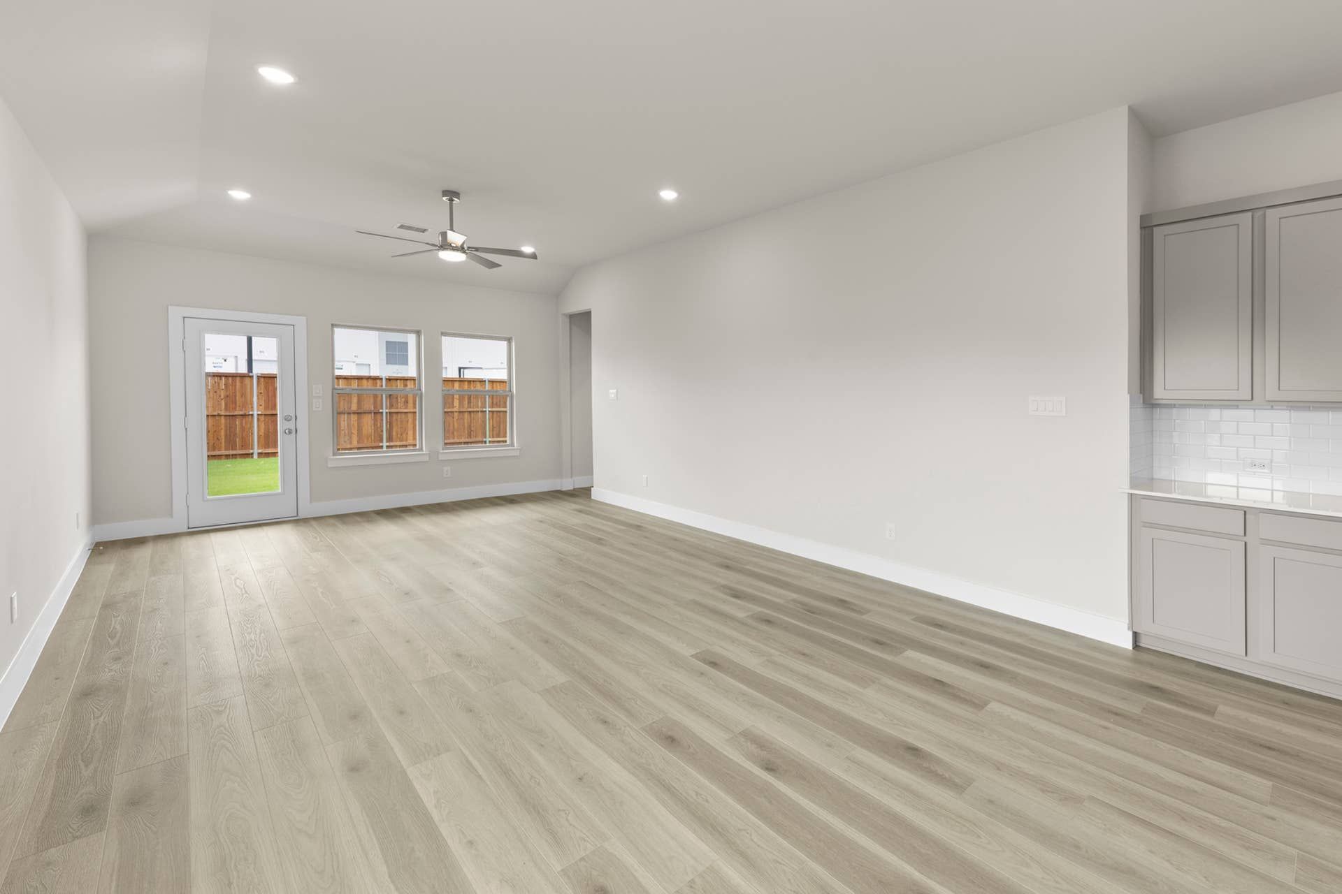 Spacious dining area with wood flooring and natural light, adjacent to modern kitchen.