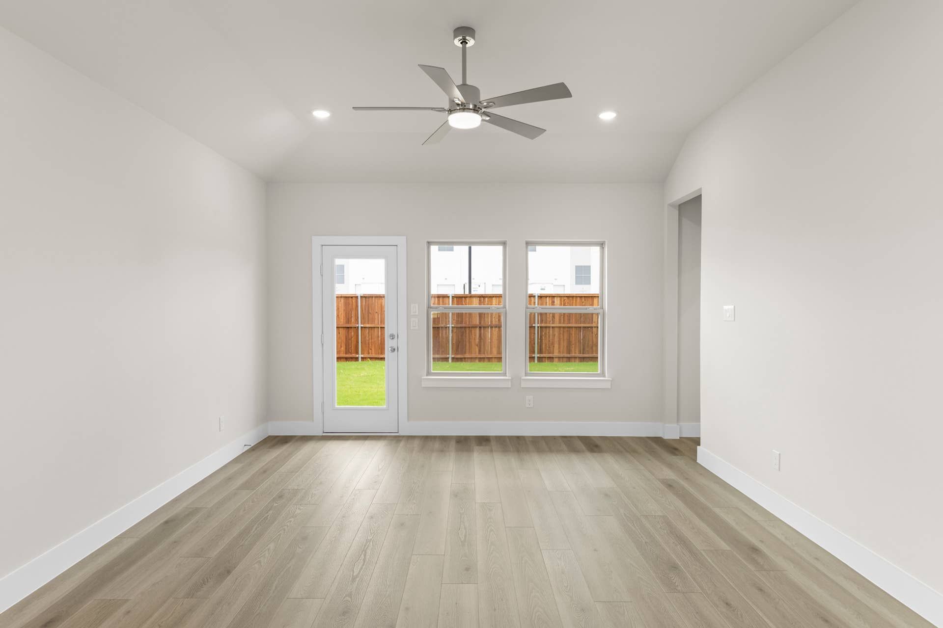 Modern living room with wood flooring, ceiling fan, and patio doors.