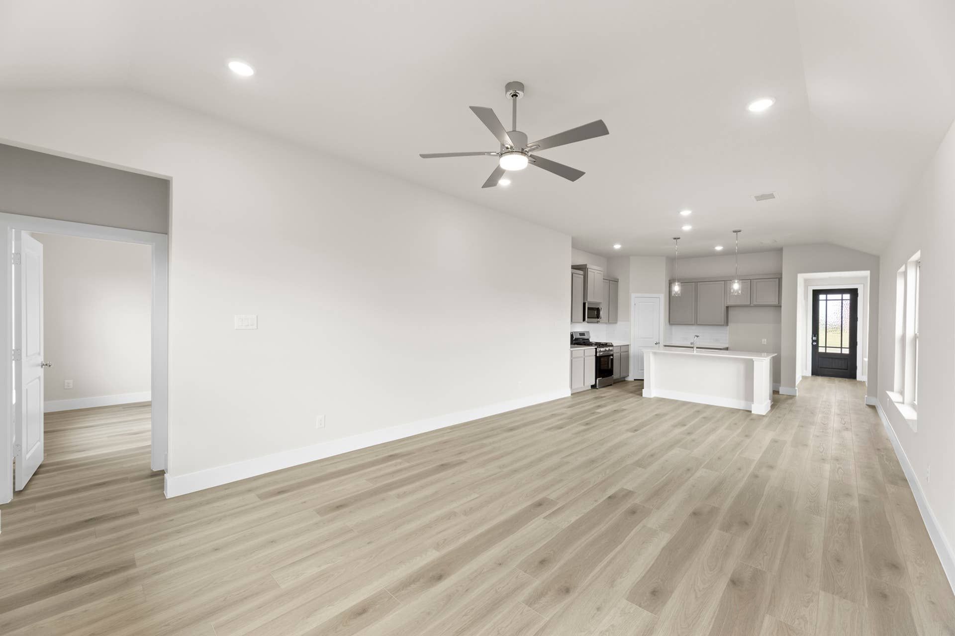 Spacious open-concept living area with modern kitchen and wood-style flooring.