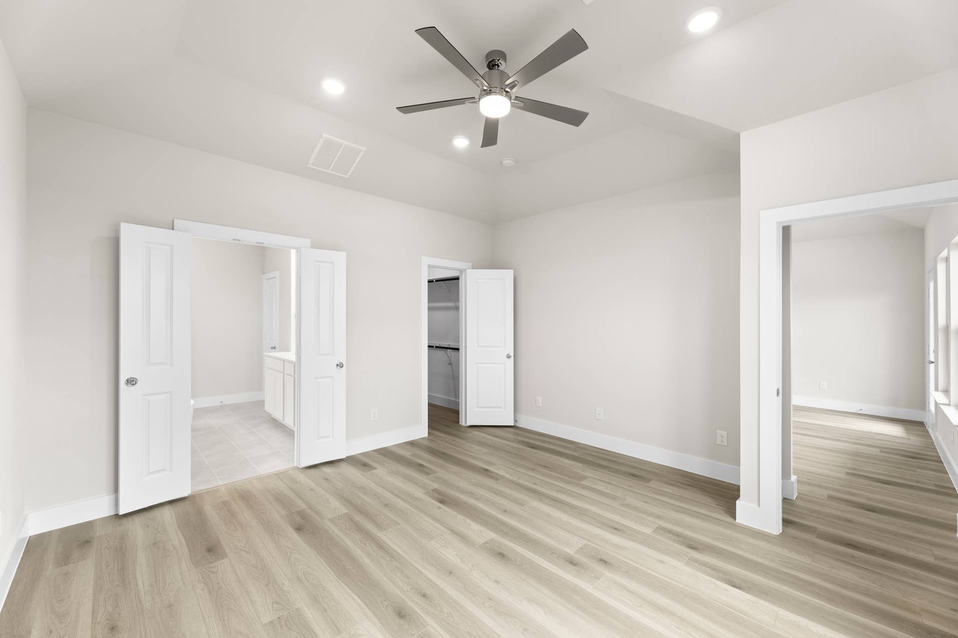 Spacious primary bedroom interior with ceiling fan and walk-in closet access.