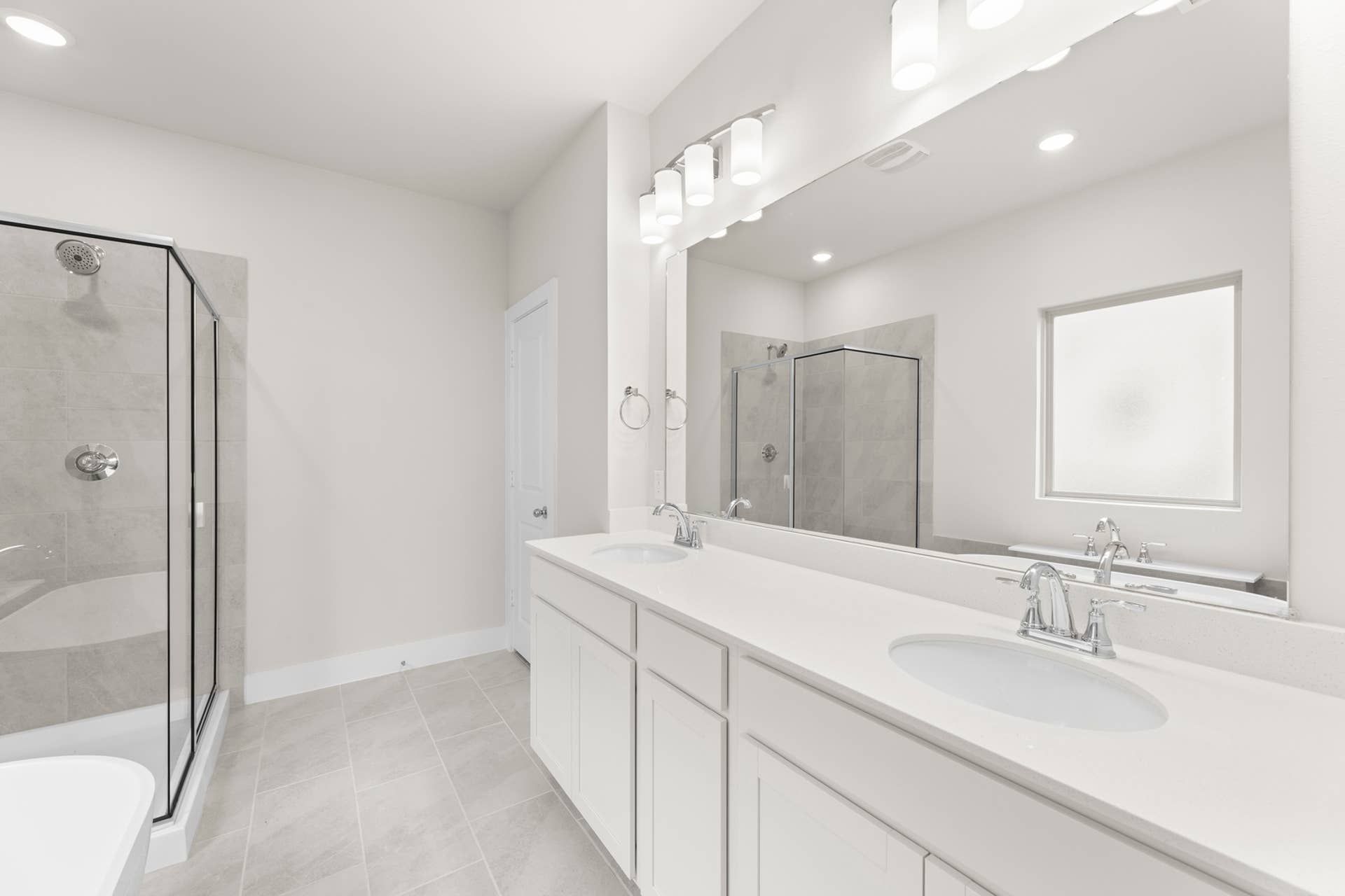 Modern bathroom with dual sinks, glass shower, and large mirror.