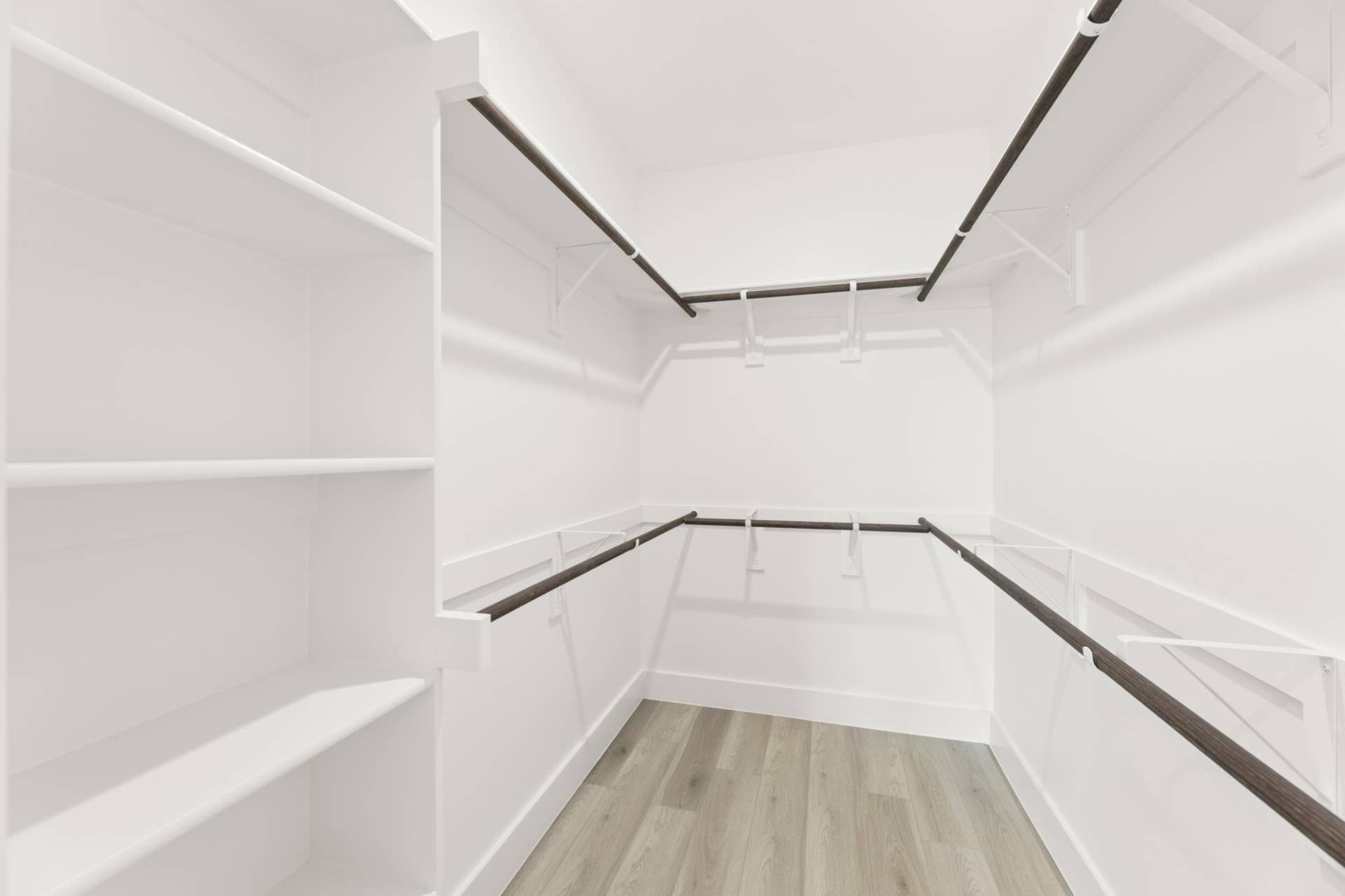 Spacious walk-in closet with wooden rods and built-in shelving.