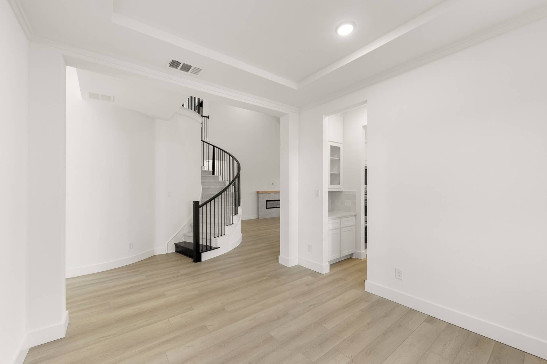 Modern interior with spiral staircase and light wood flooring.