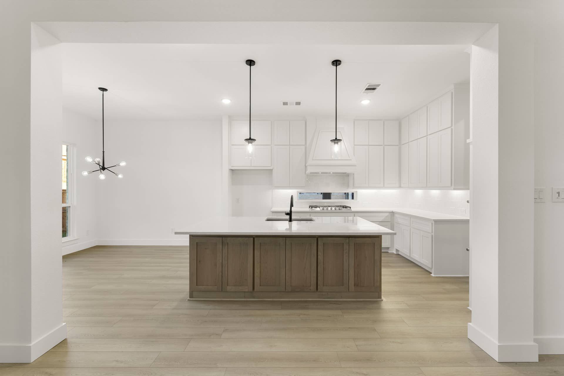 Modern kitchen with pendant lights, white cabinets, and large central island.