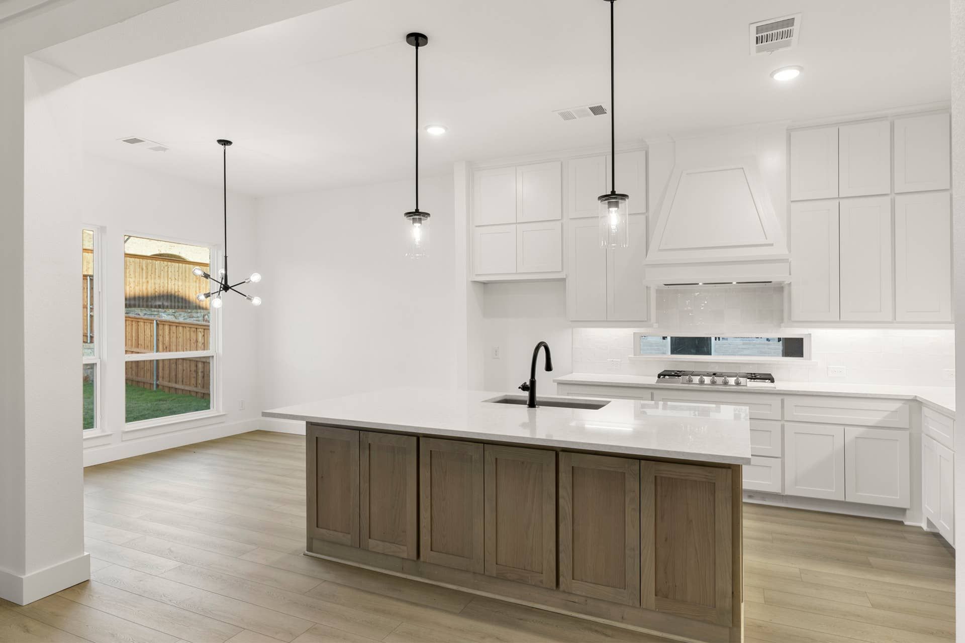 Modern kitchen with white cabinetry, island, and pendant lighting.