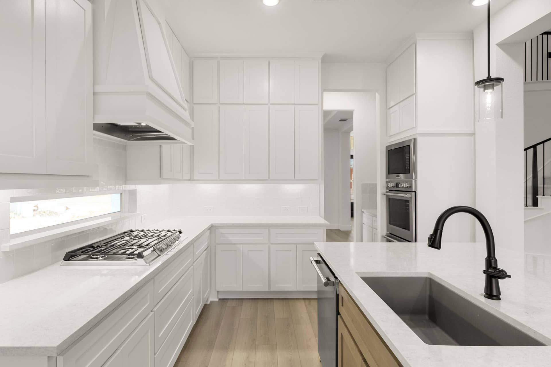 Modern kitchen with white cabinetry, island sink, and stainless steel appliances.