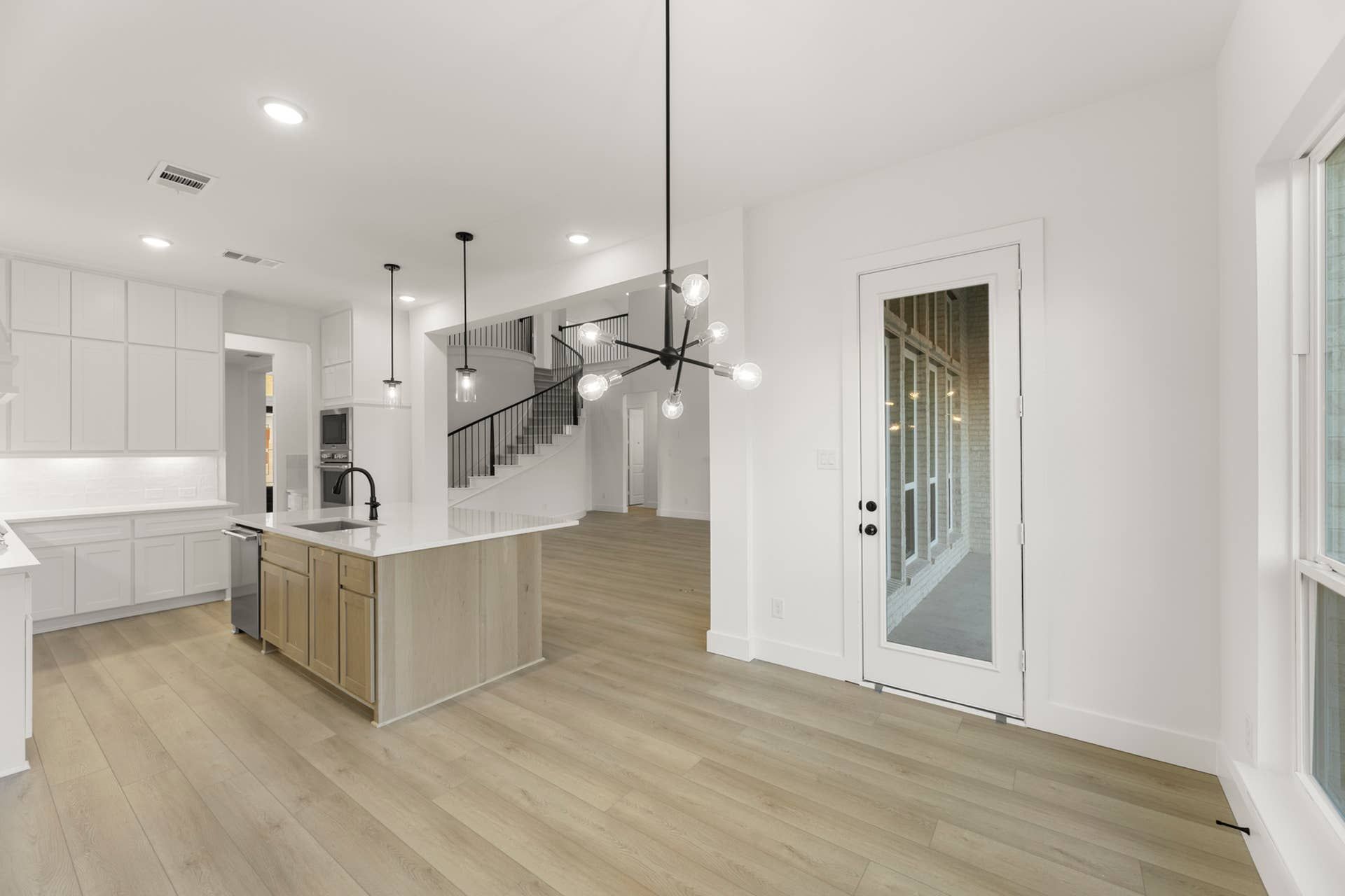Modern kitchen interior with island, pendant lighting, and hardwood floors.