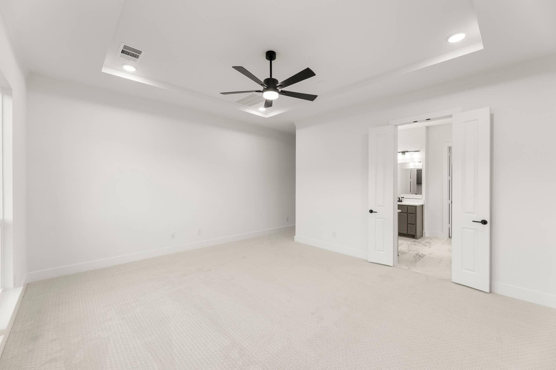 Spacious bedroom with tray ceiling, ceiling fan, and ensuite bathroom access.