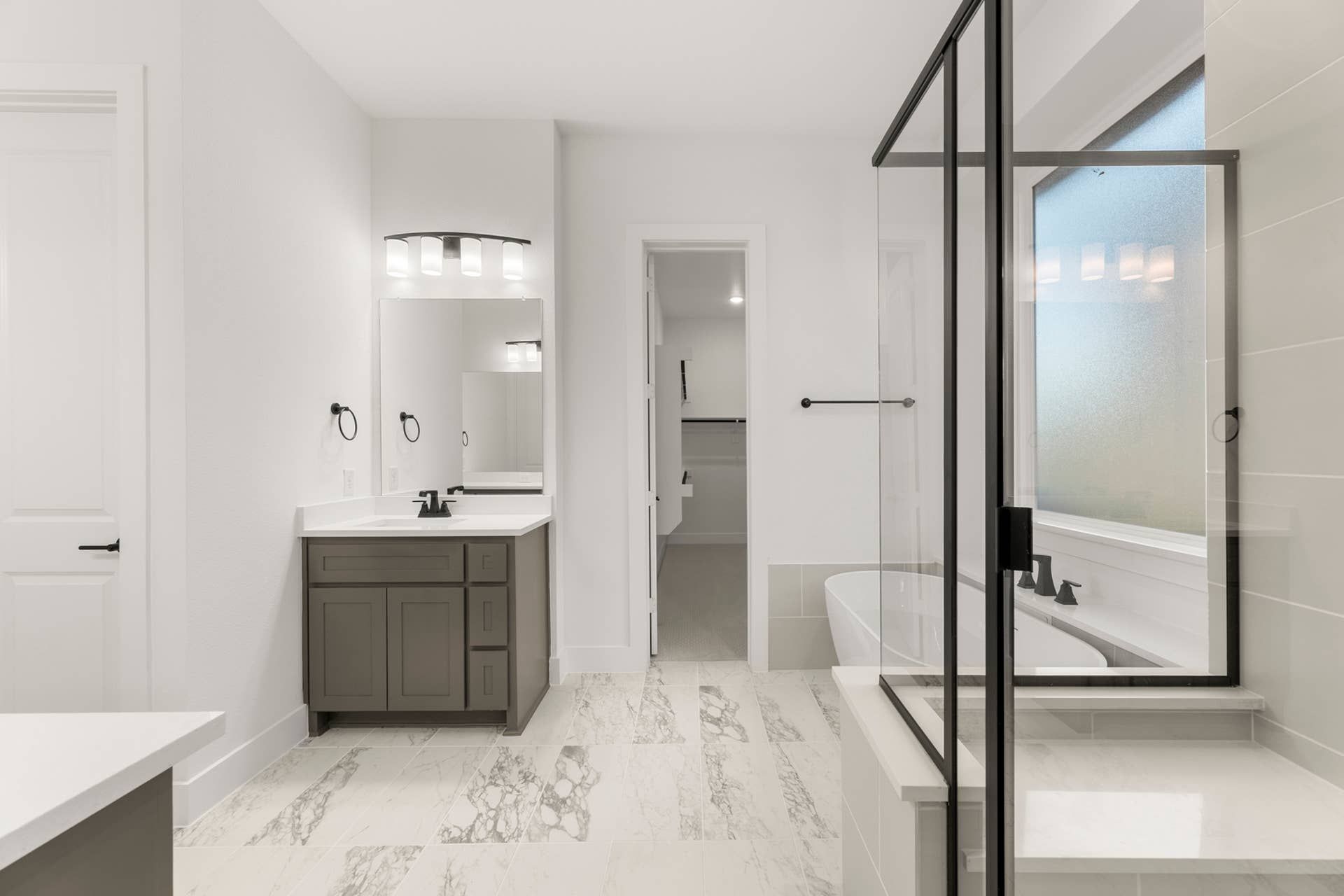 Modern bathroom with marble floors, glass shower, and sleek vanity.