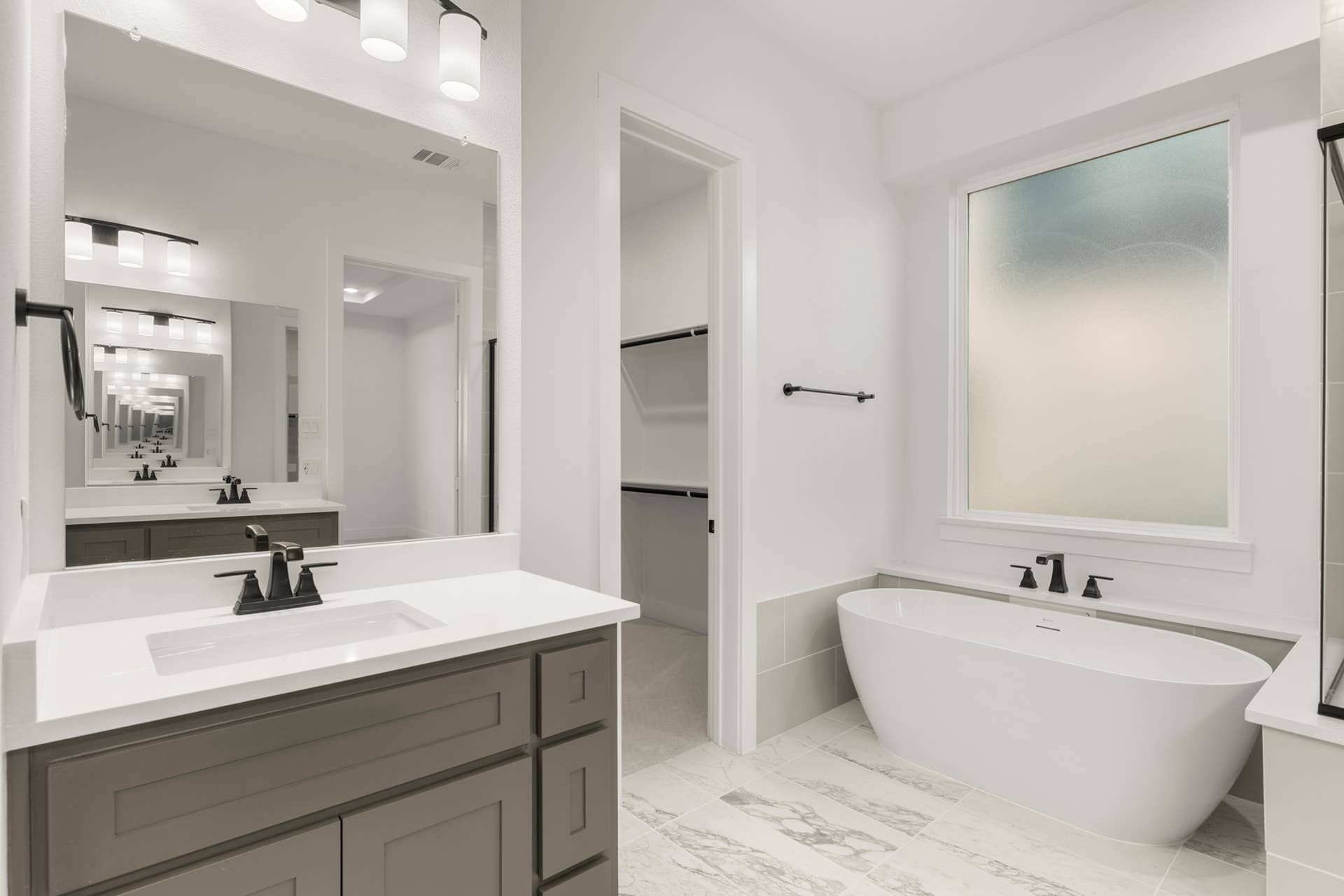 Modern bathroom with freestanding tub, large mirror, and elegant lighting.