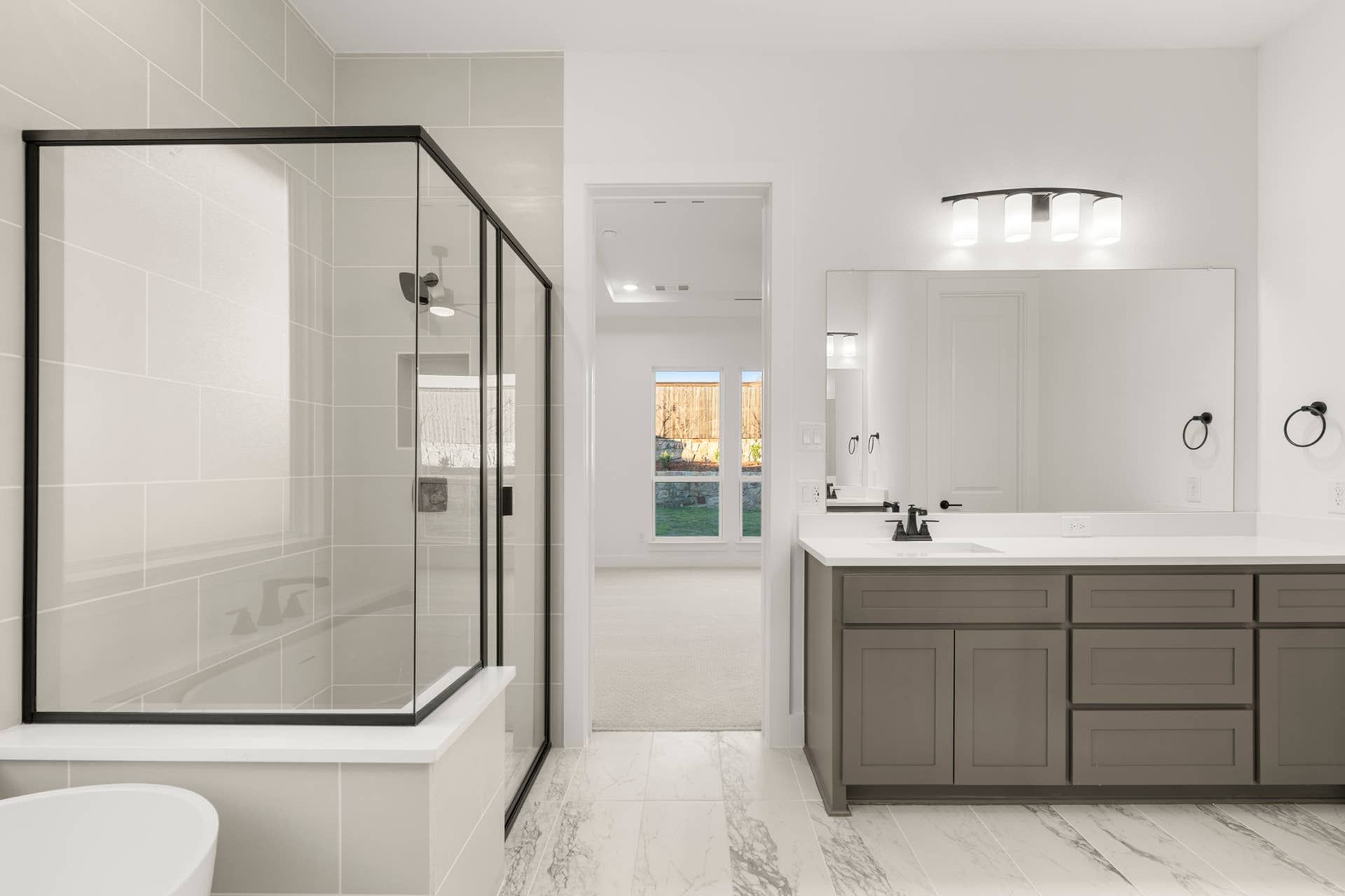 Modern bathroom with glass shower, dual vanity, and marble tile flooring.