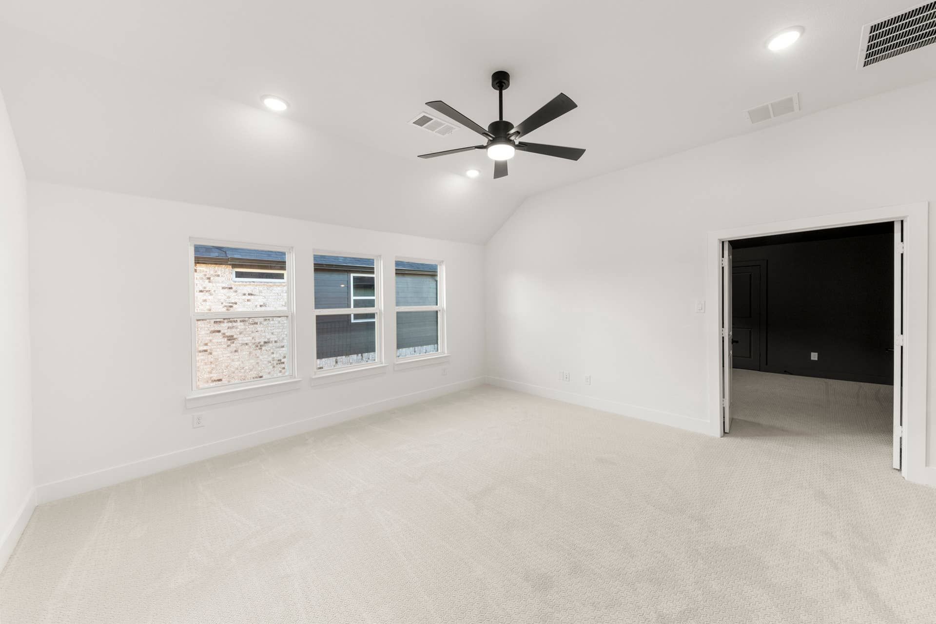 Spacious interior room with ceiling fan, recessed lighting, and multiple windows.