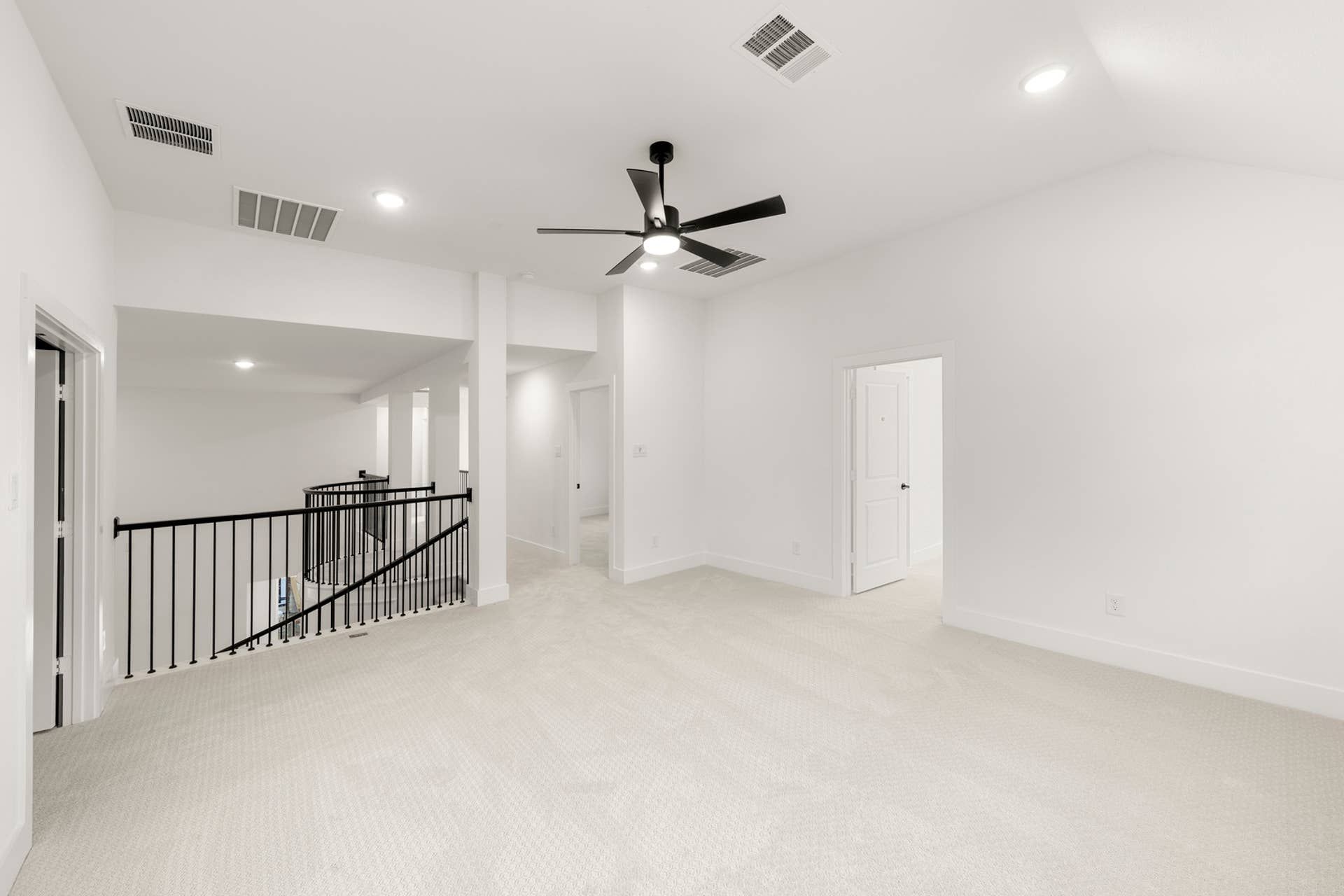 Spacious upstairs game room with ceiling fan and carpeted flooring.
