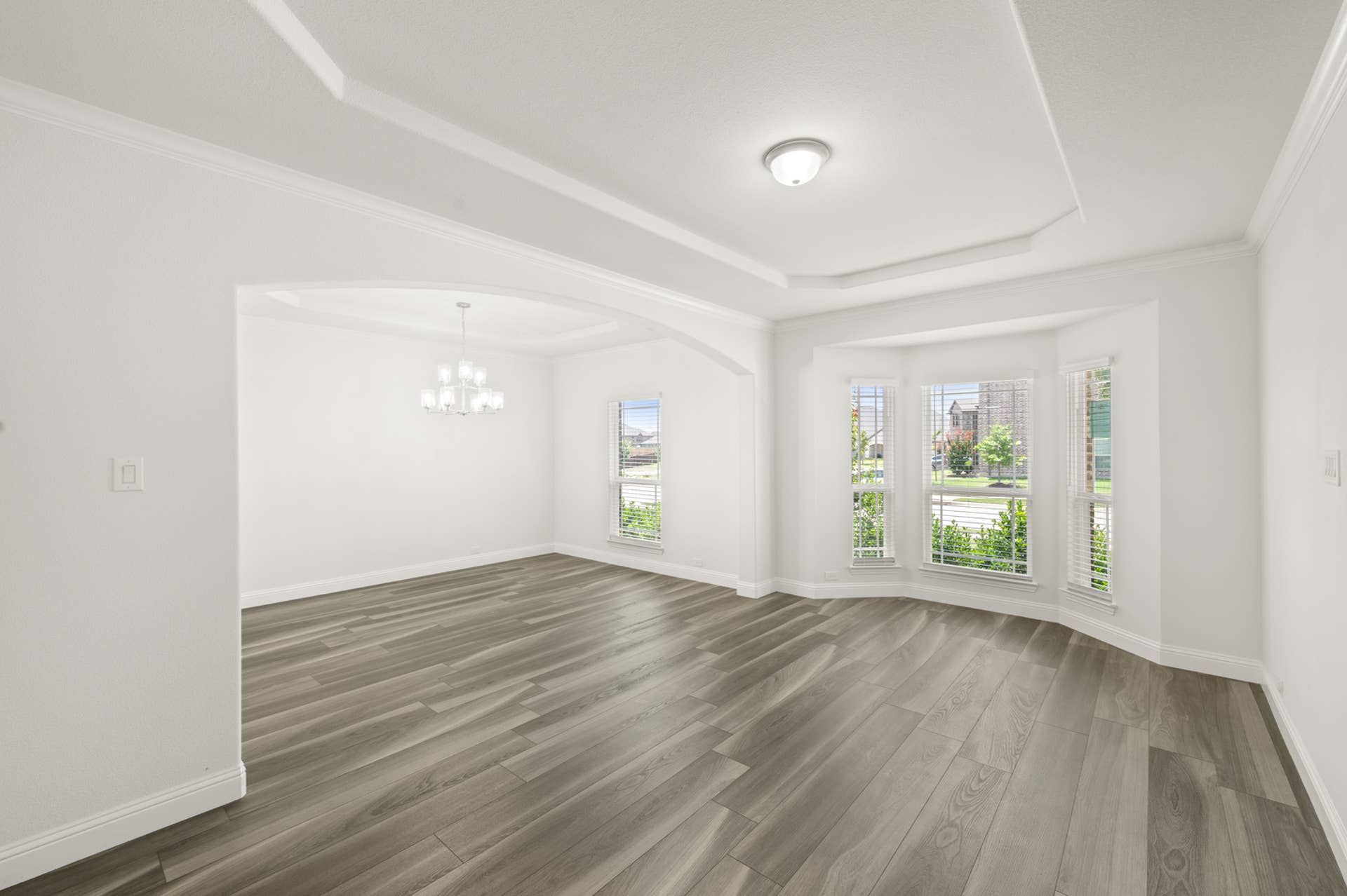 Spacious interior with large windows, modern chandelier, and hardwood flooring.