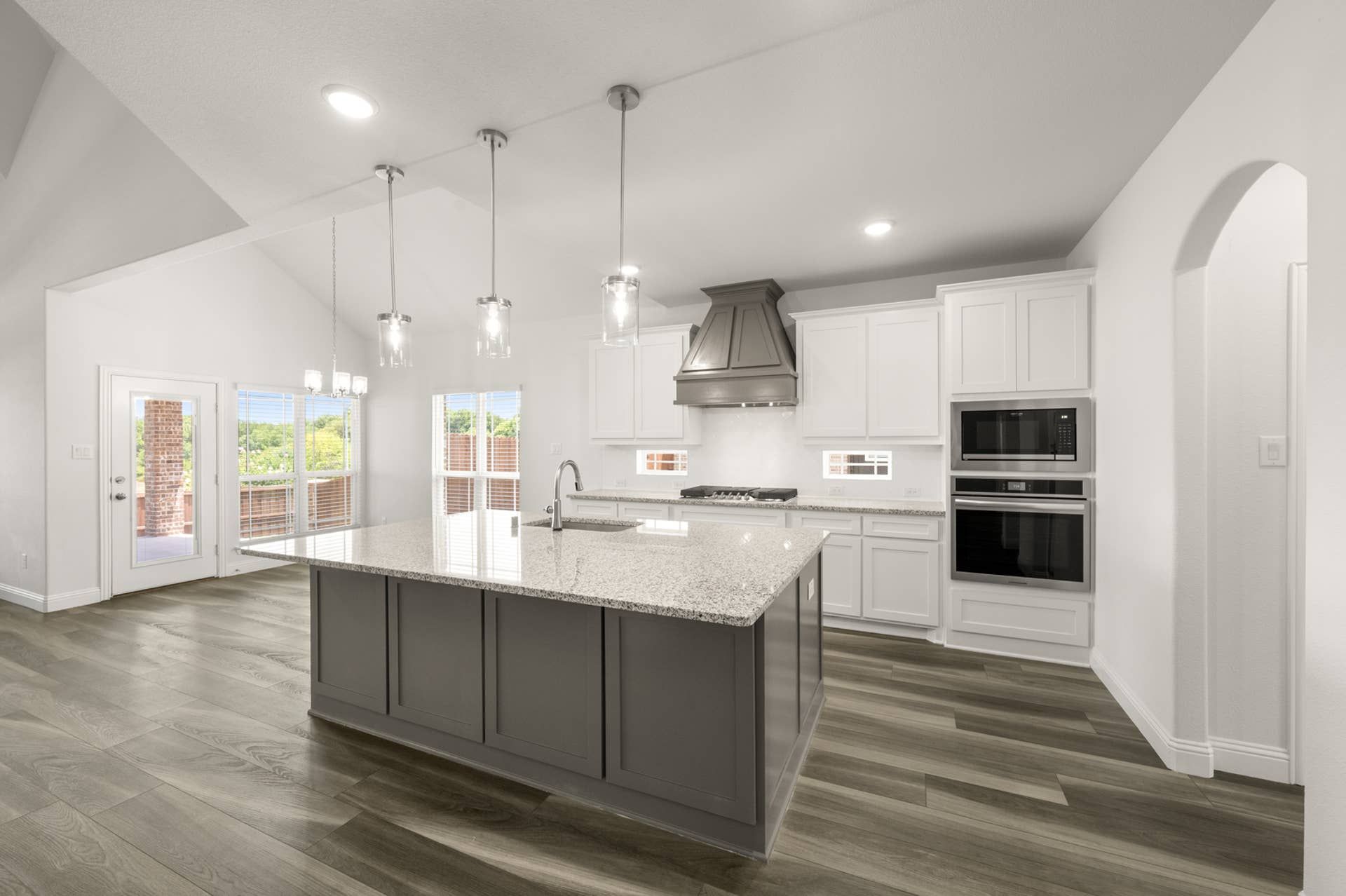 Modern kitchen with granite island, pendant lighting, and wood flooring.
