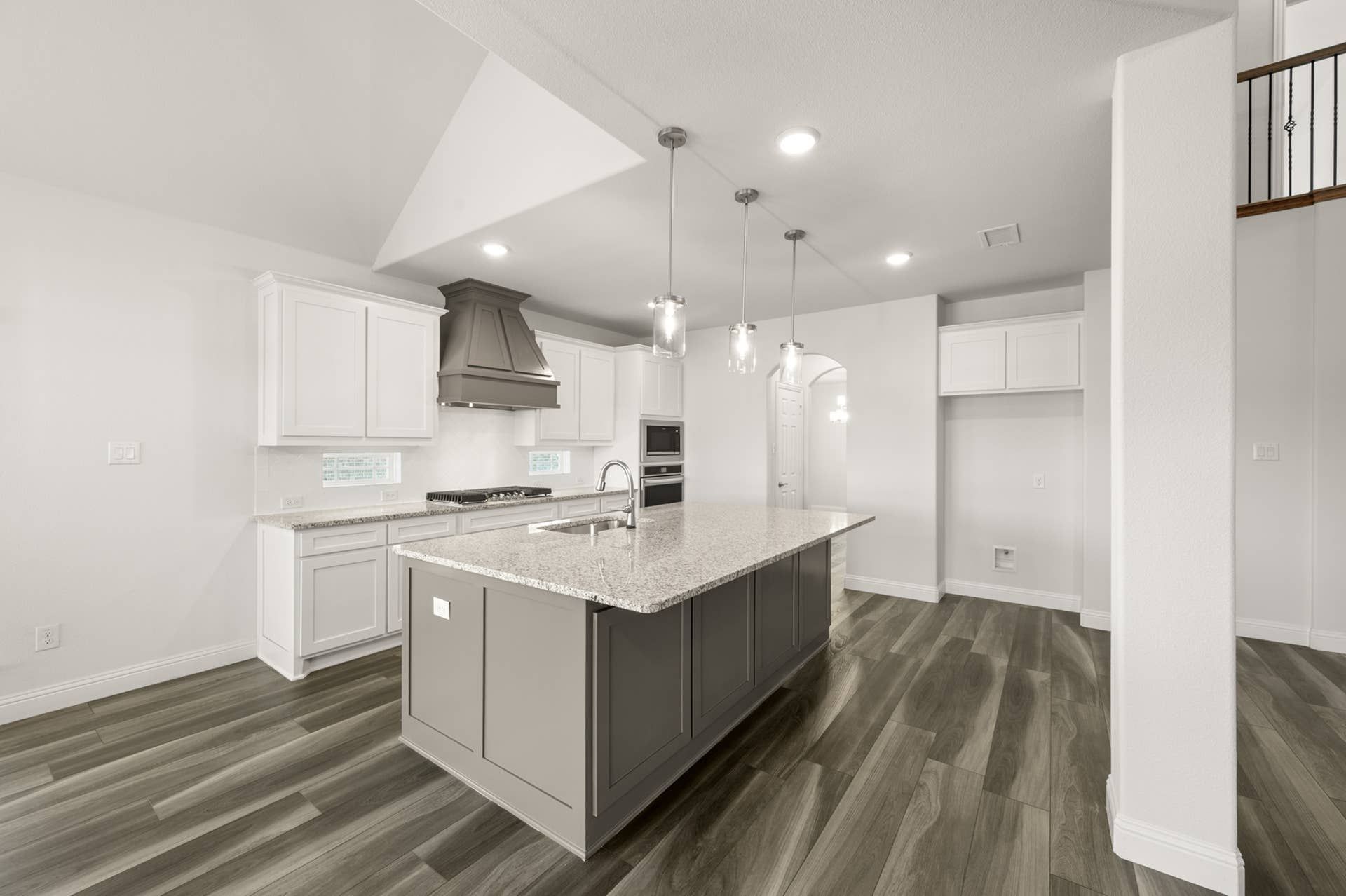 Modern kitchen with island, pendant lights, and wood flooring.