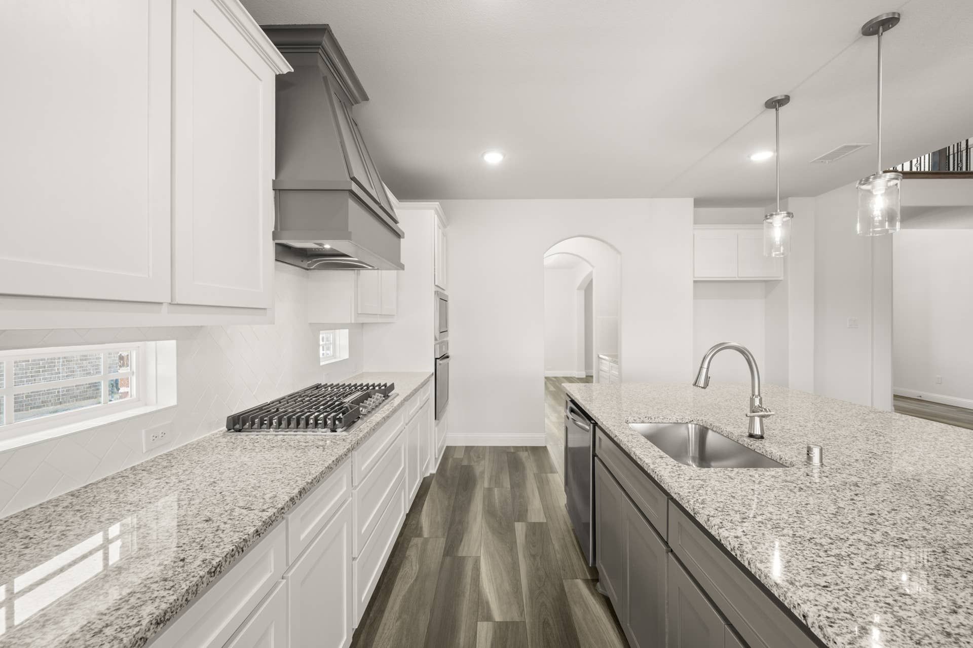 Modern kitchen with granite countertops, pendant lighting, and stainless steel appliances.
