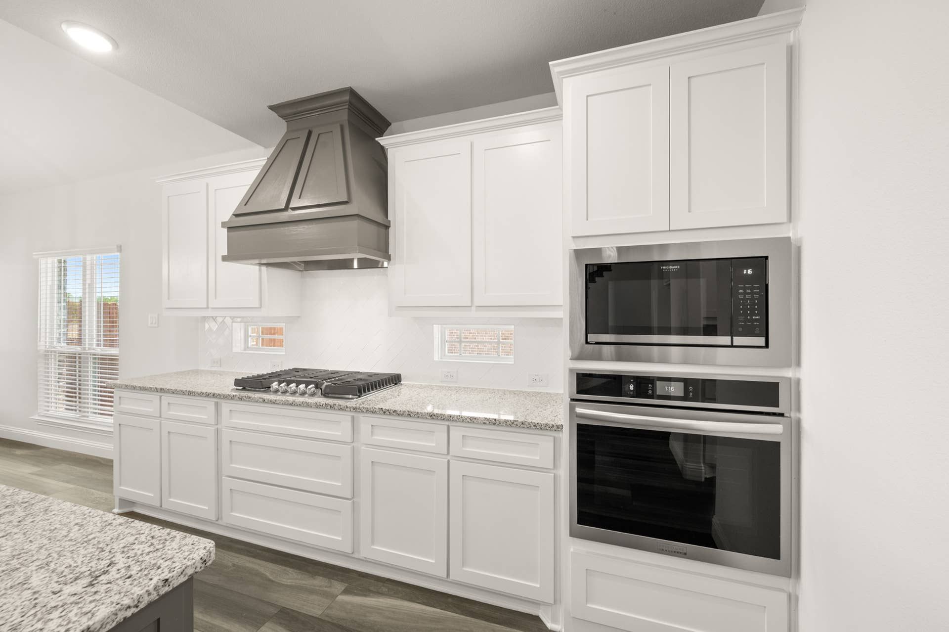 Modern kitchen with white cabinetry, granite countertops, and stainless steel appliances.