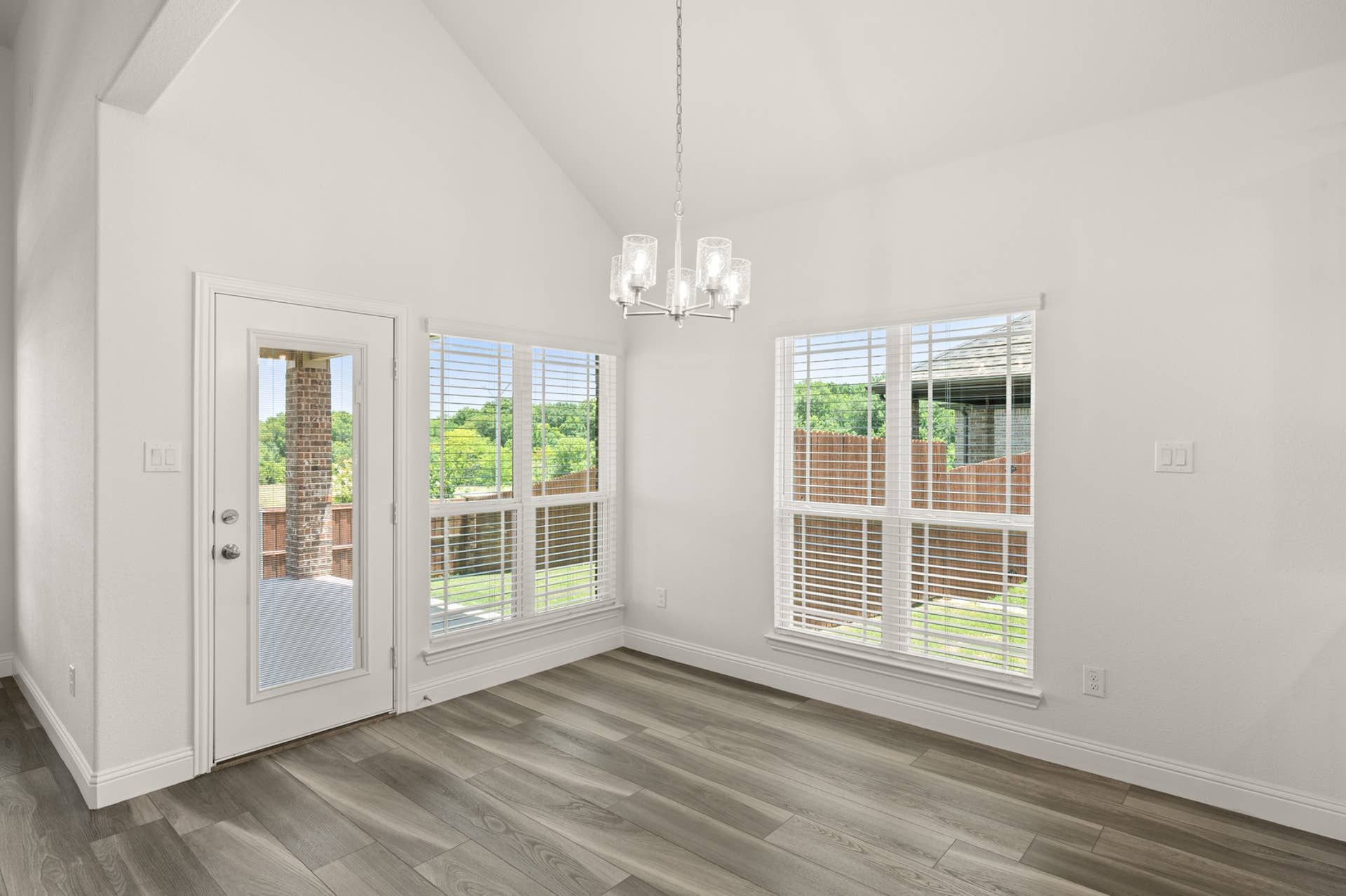 Bright breakfast nook with large windows and modern chandelier.
