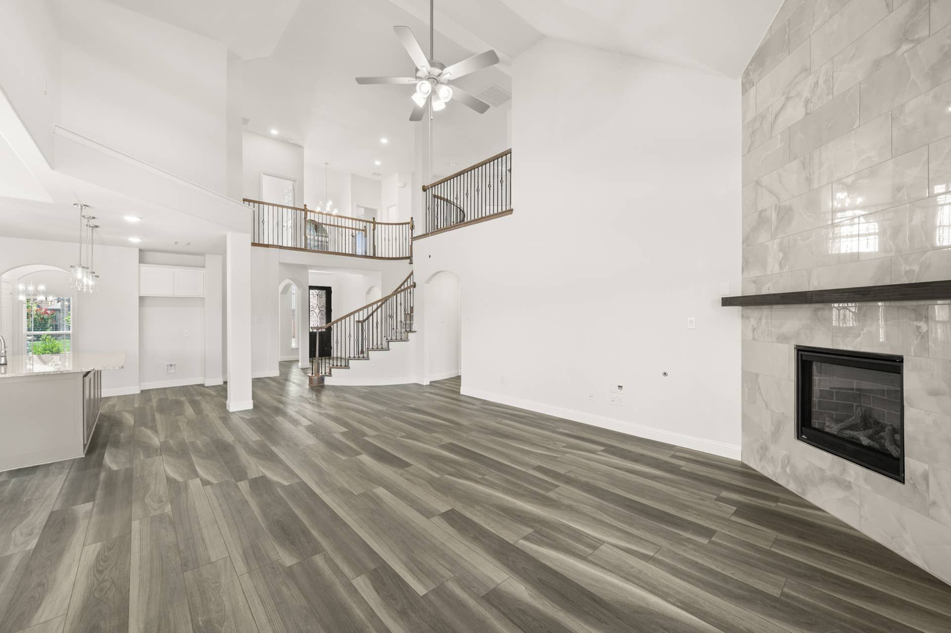 Spacious living room with vaulted ceiling, modern fireplace, and elegant staircase.
