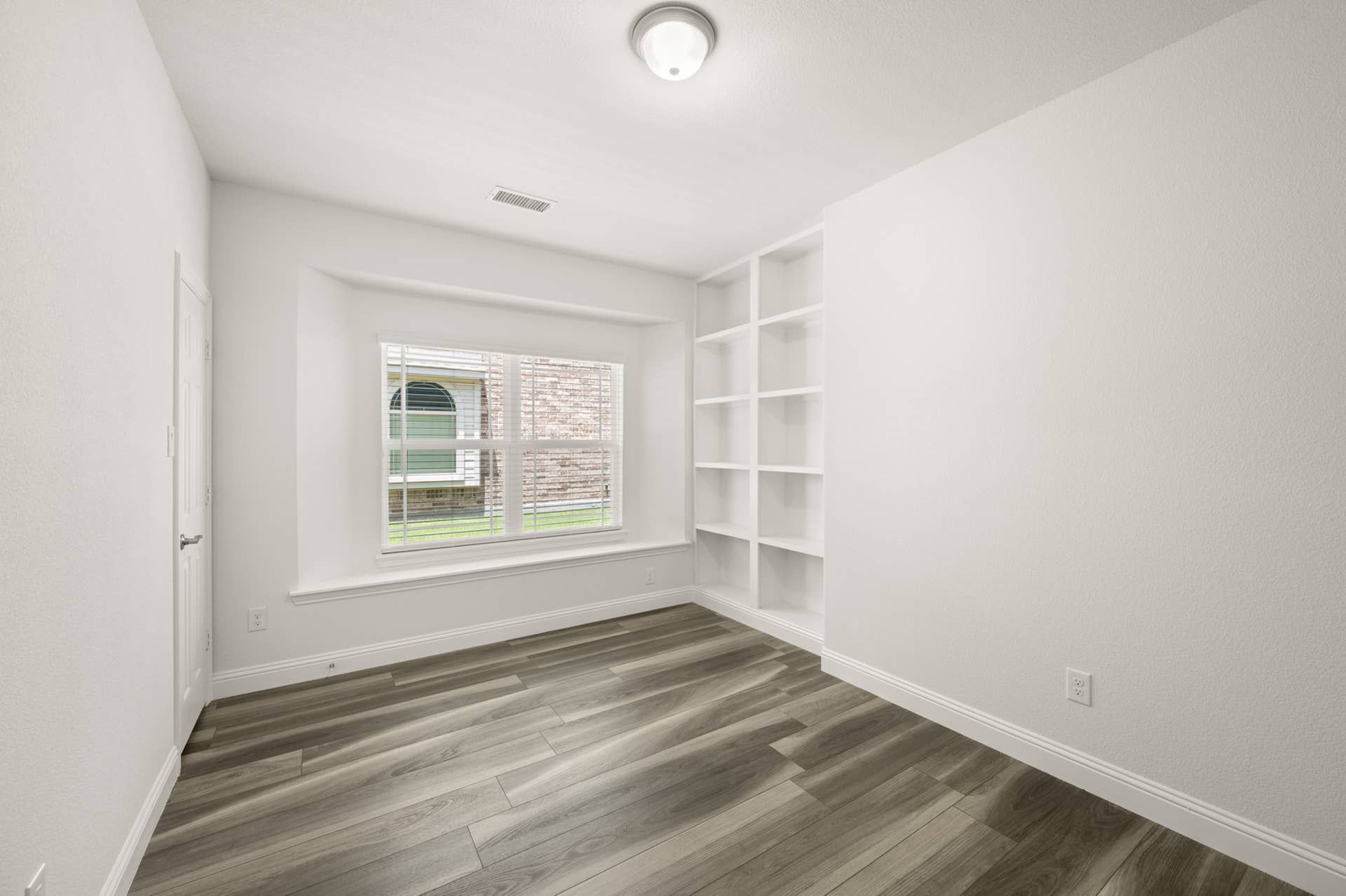 Bright study room with built-in shelves and large window.