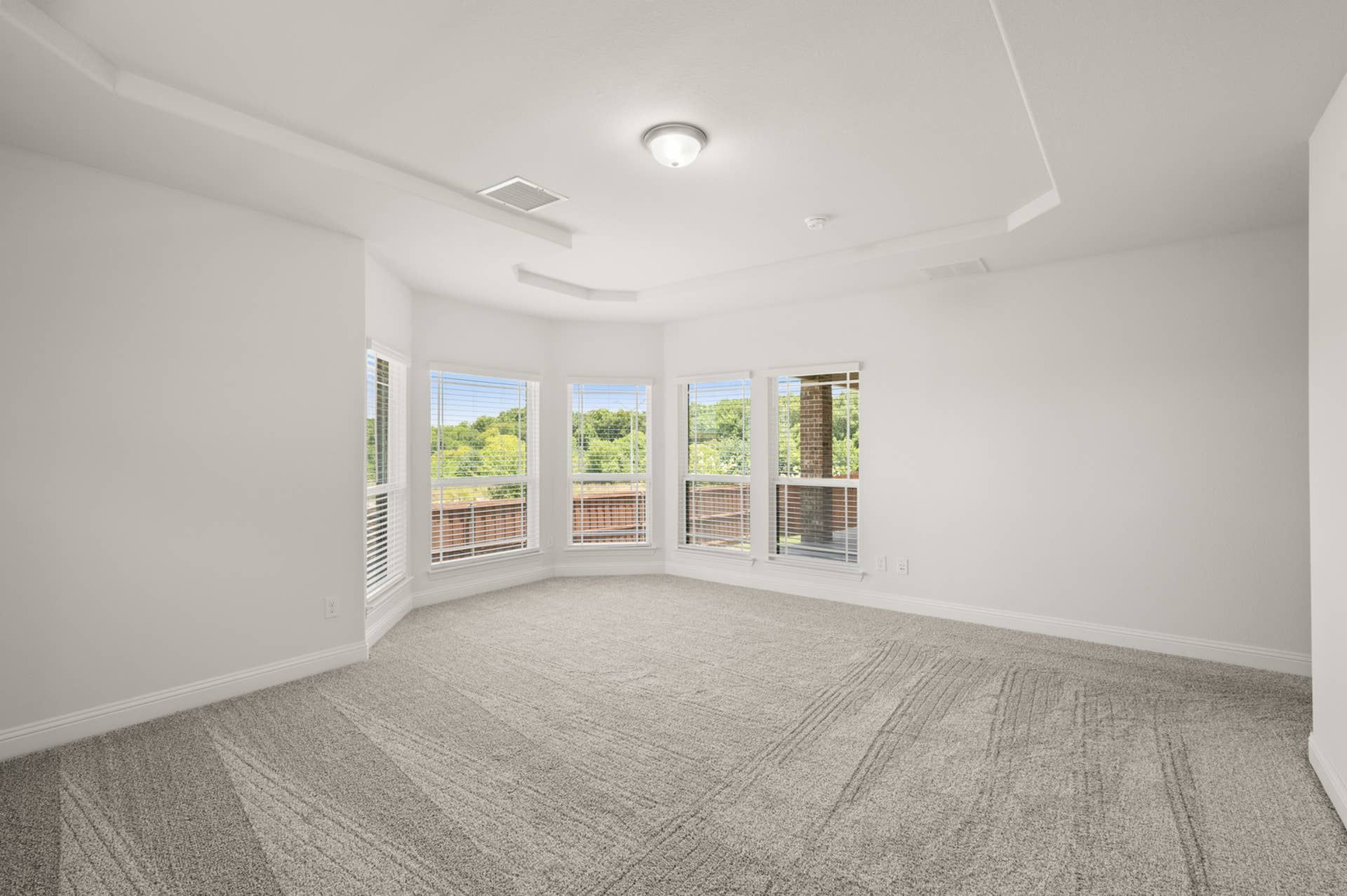 Spacious primary suite with large windows and plush carpeting.
