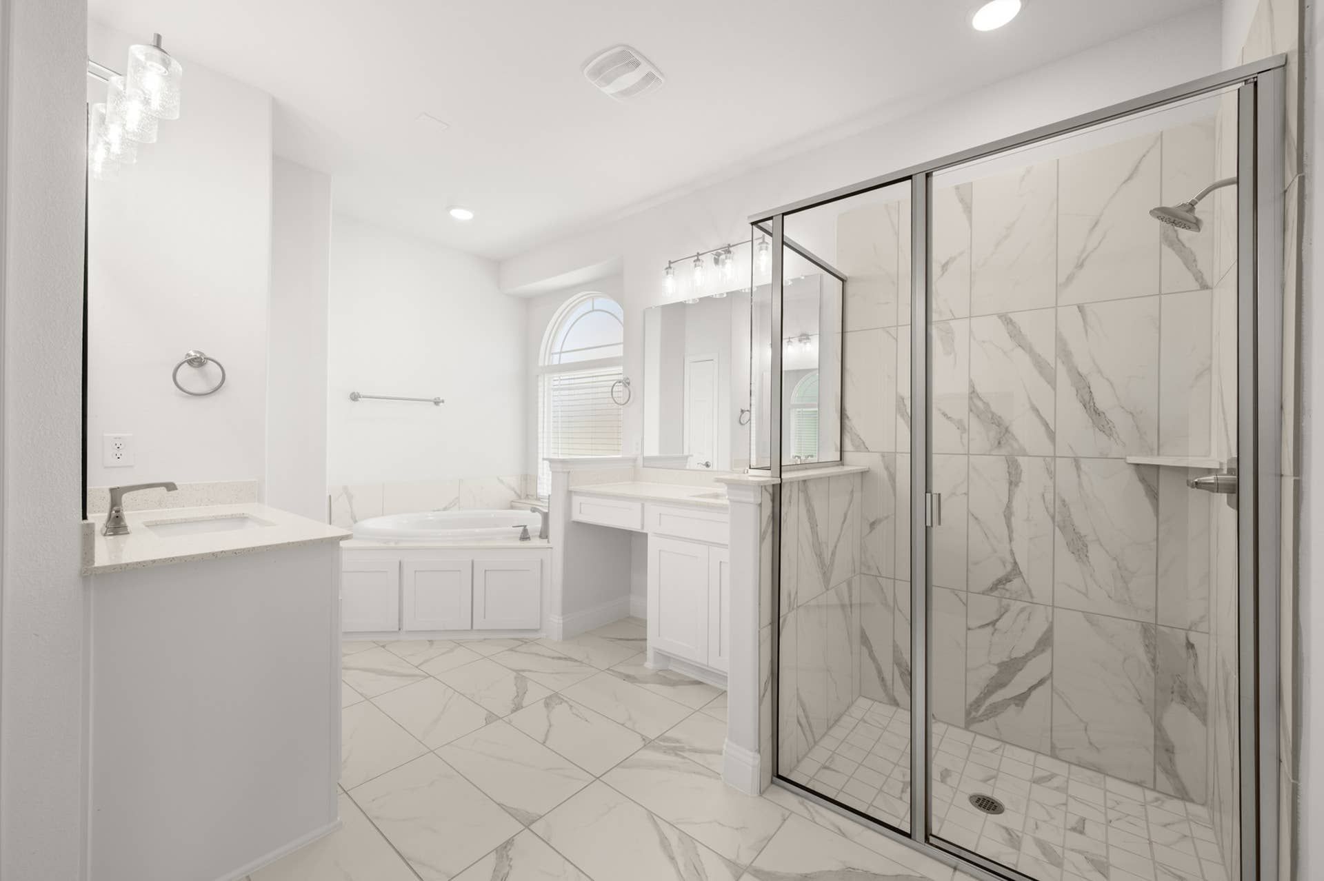 Luxurious bathroom with marble tiles, glass shower, and elegant double vanity.
