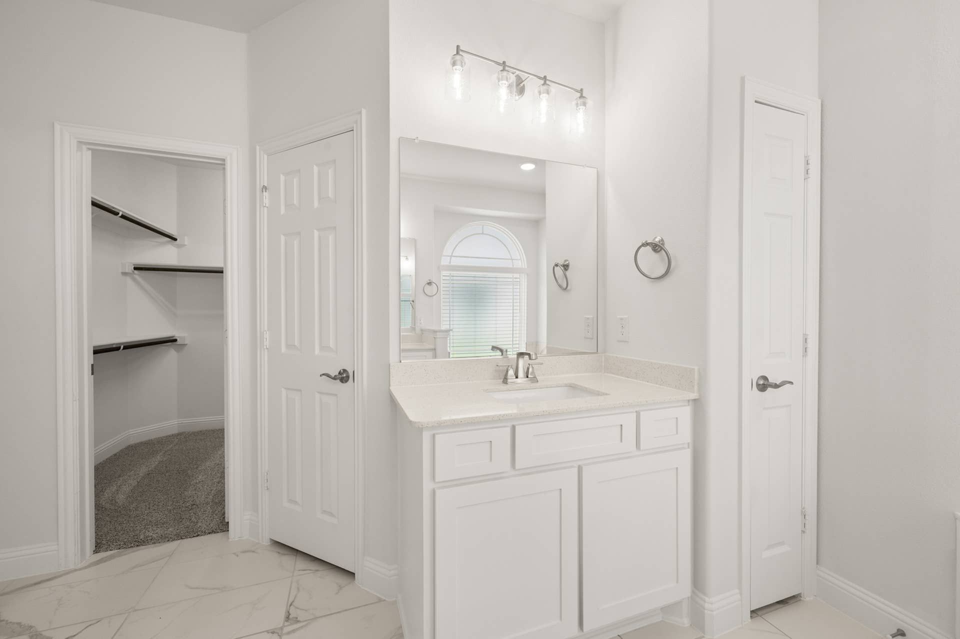 Bright primary suite bathroom with vanity, large mirror, and walk-in closet.