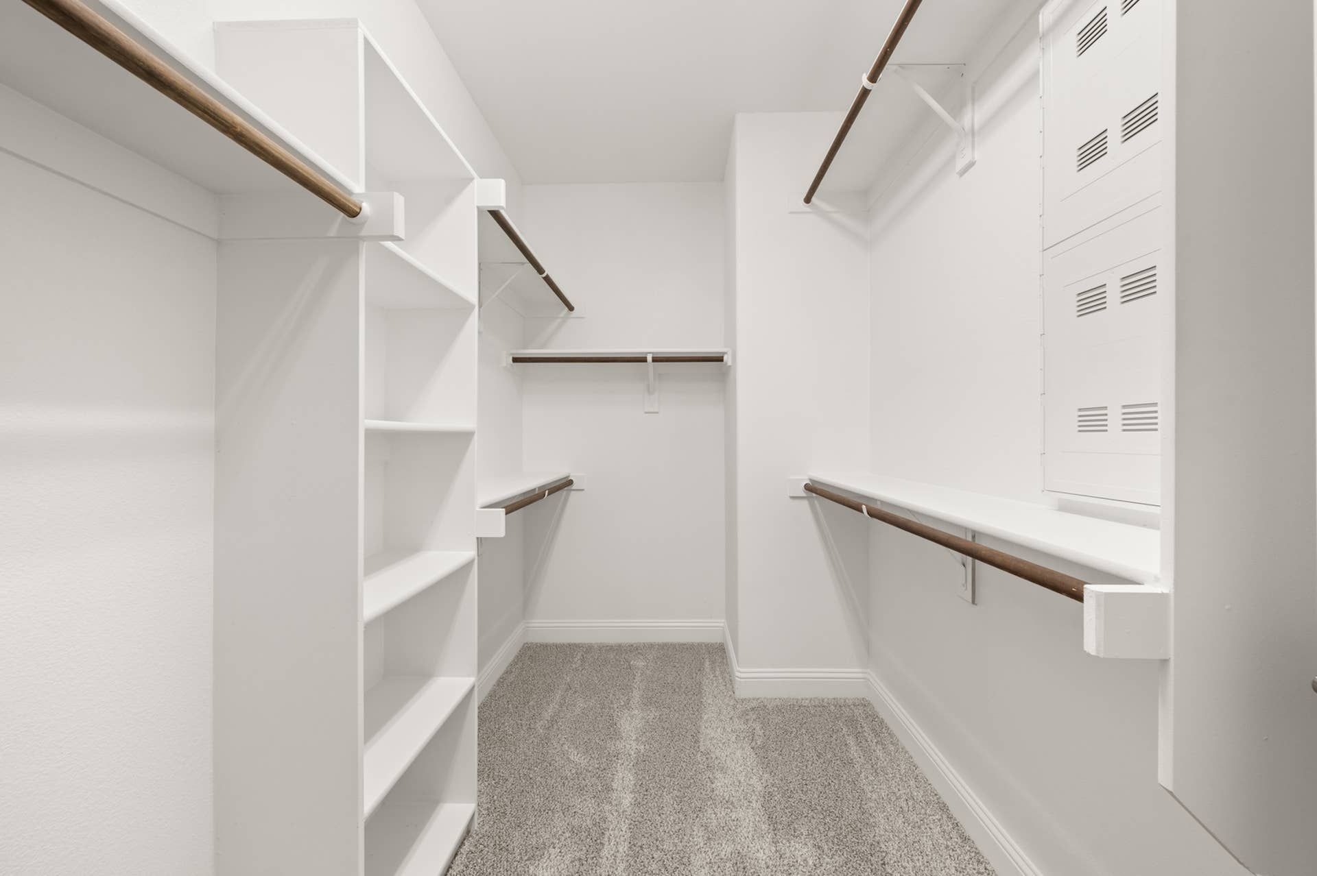 Spacious walk-in closet with white shelves and hanging rods.