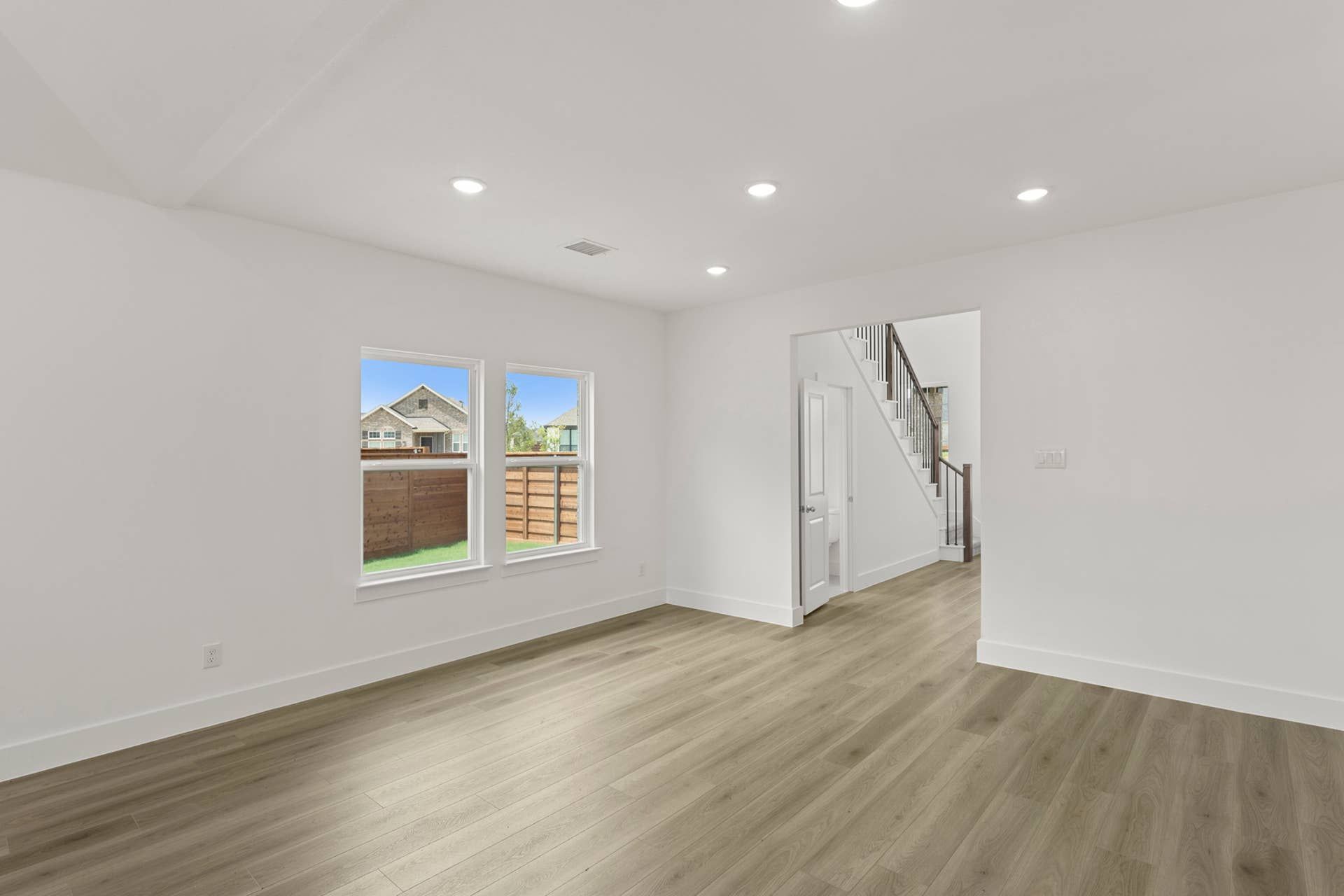 Spacious dining room with hardwood floors and recessed lighting.