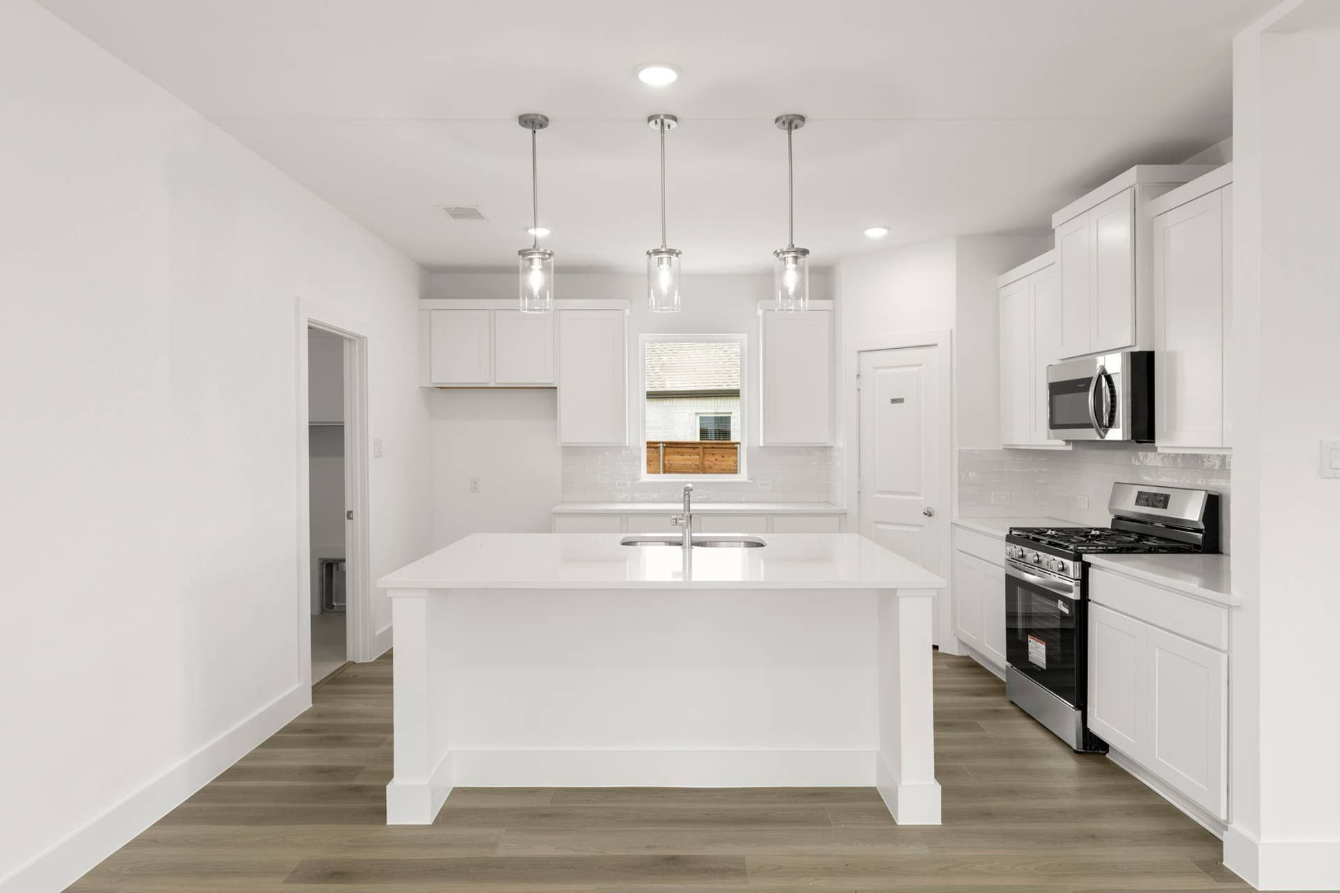 Modern kitchen with white cabinetry, island, and stainless steel appliances.