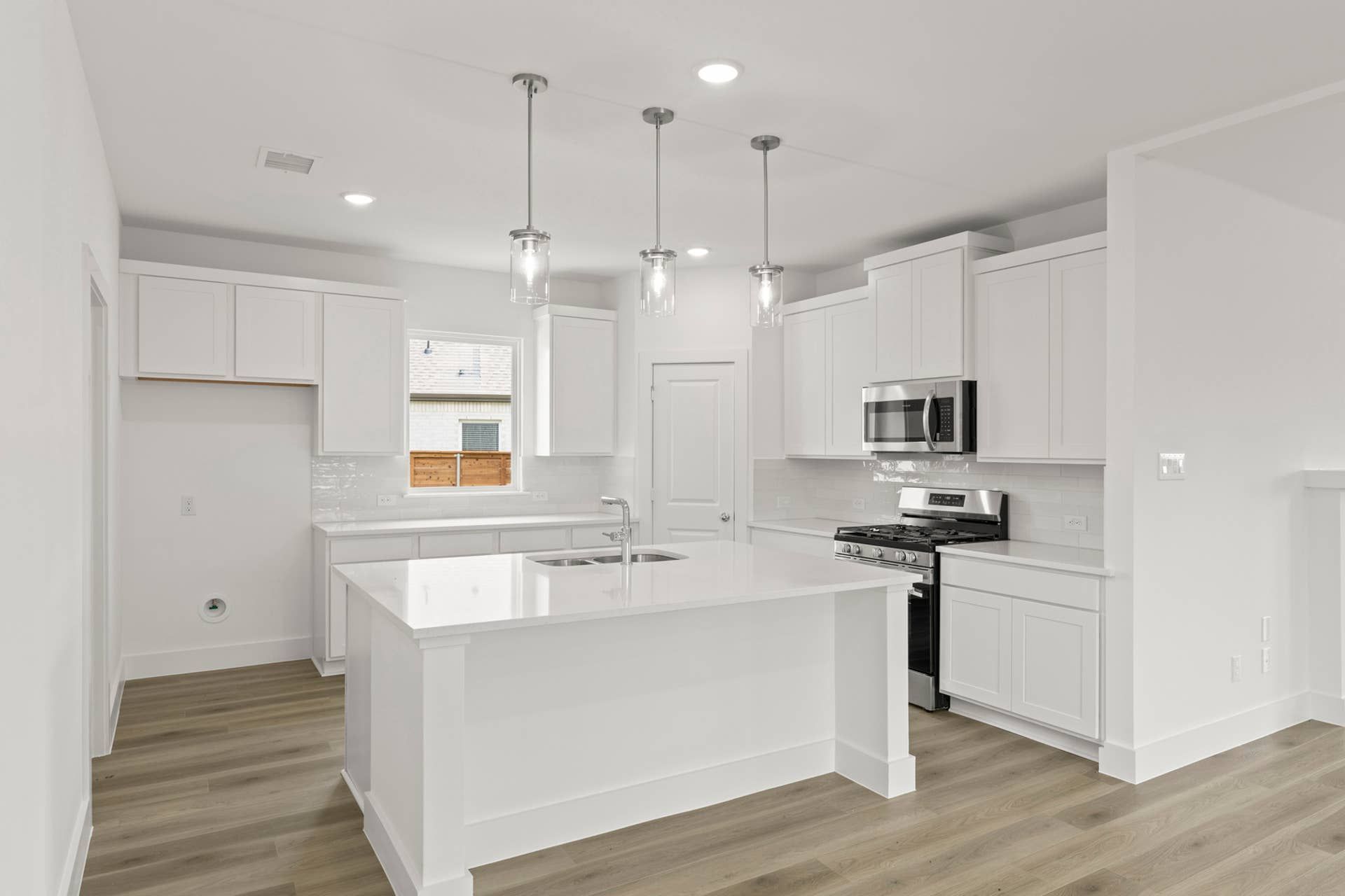Modern kitchen with white cabinetry, island, and stainless steel appliances.