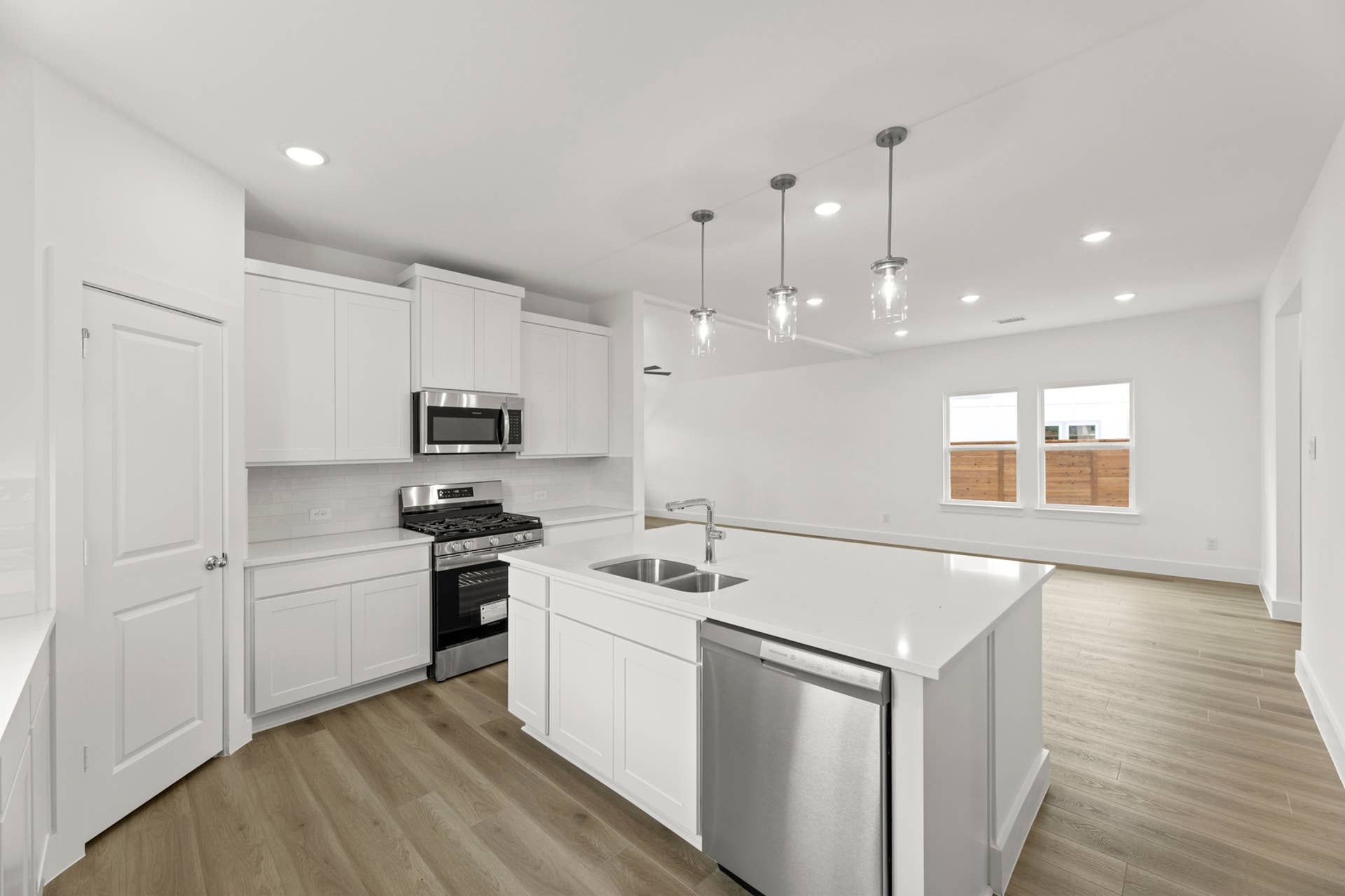 Modern kitchen with white cabinetry, stainless steel appliances, and pendant lighting.