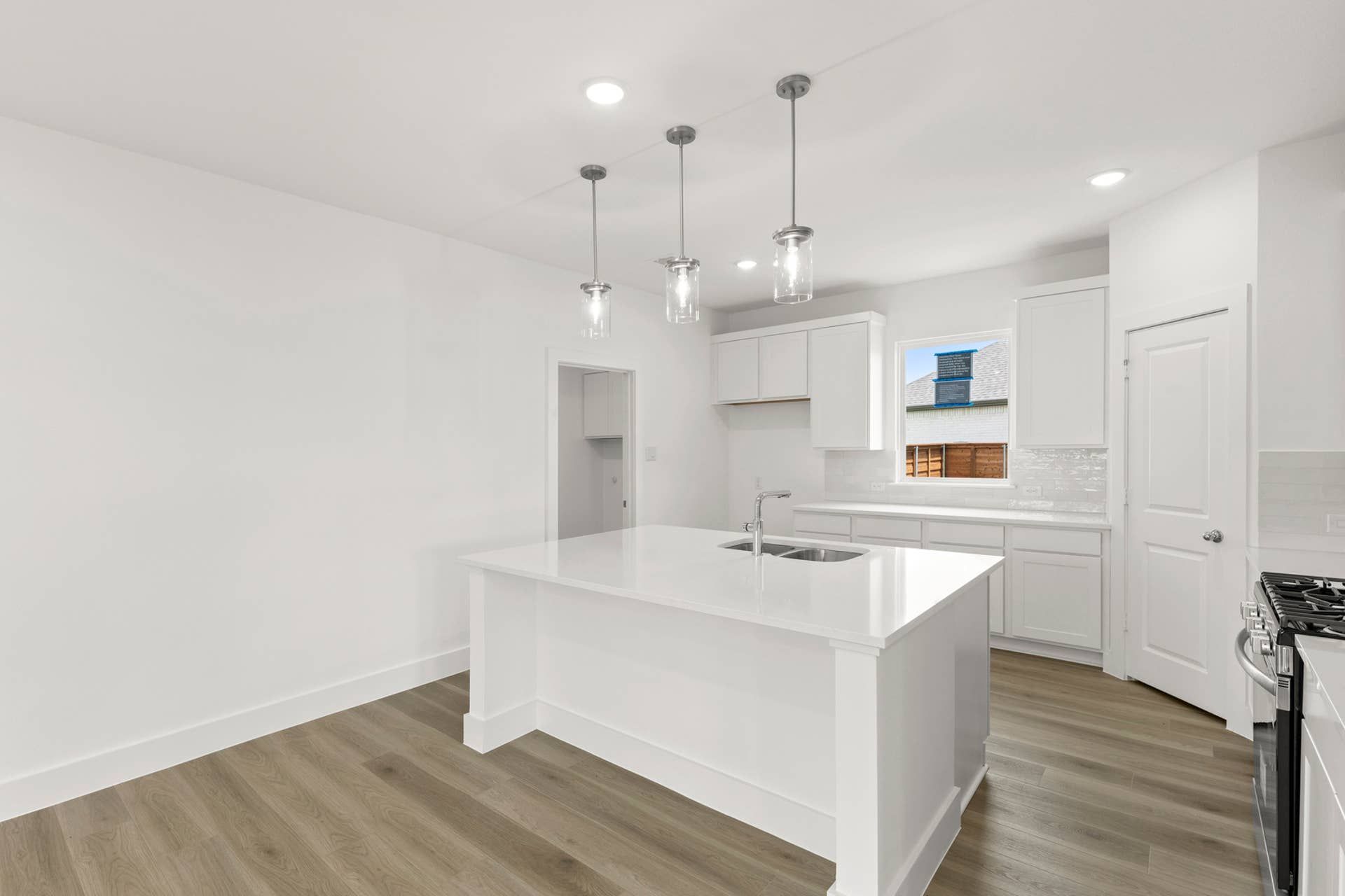 Modern kitchen with white cabinets, island, and pendant lighting.