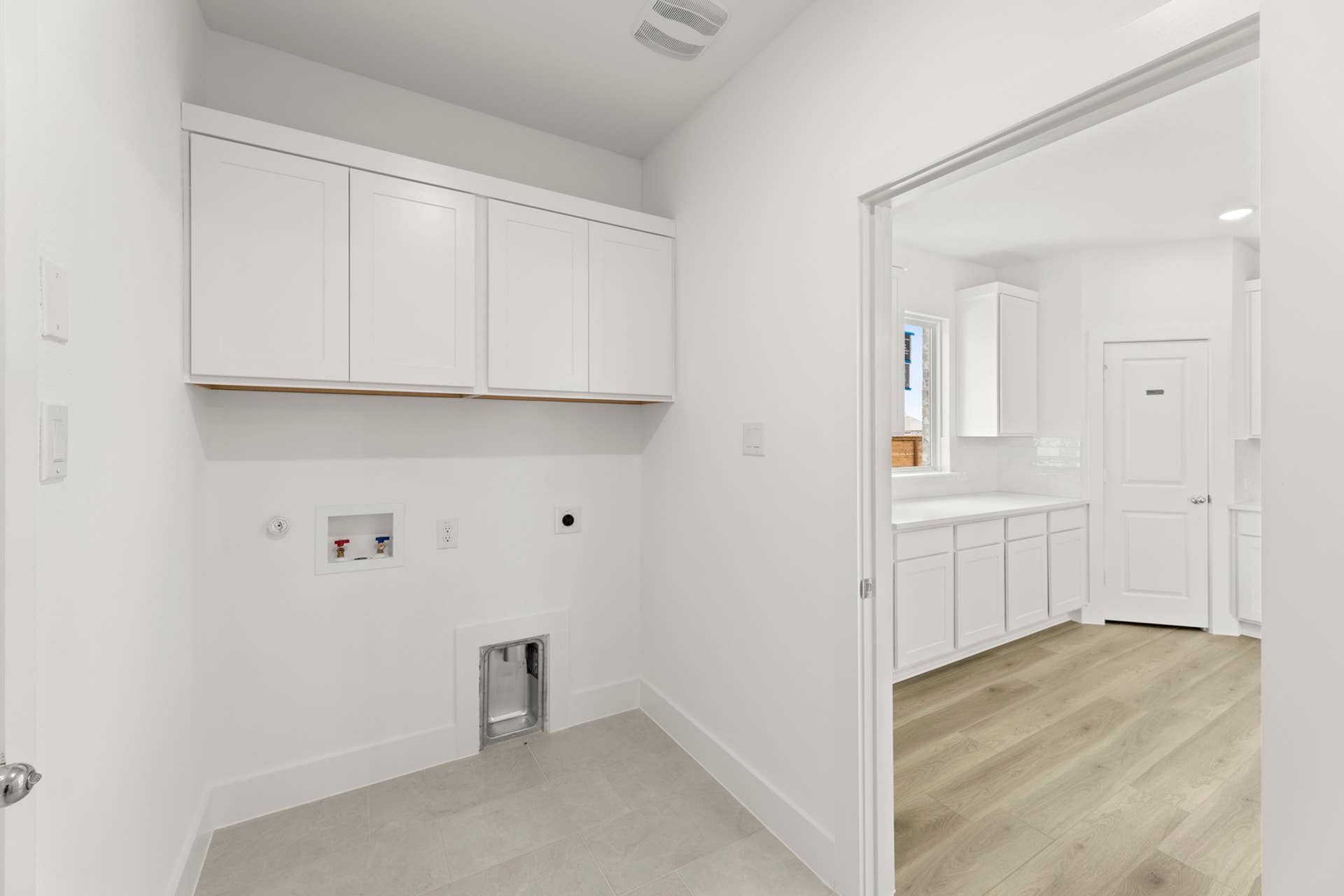 Bright utility room with white cabinetry and laundry hookups.