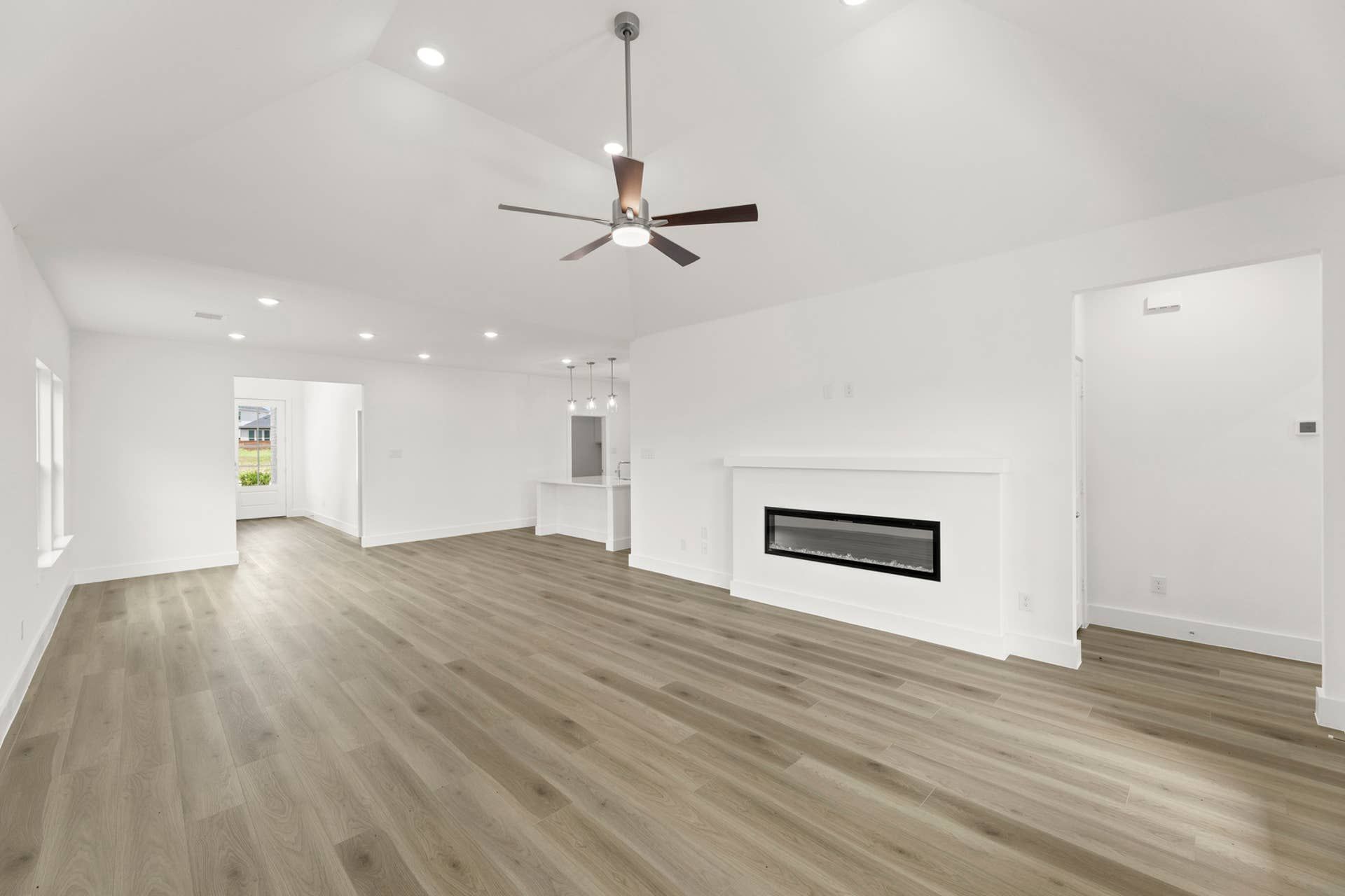 Spacious modern living room with wood flooring, ceiling fan, and built-in fireplace.