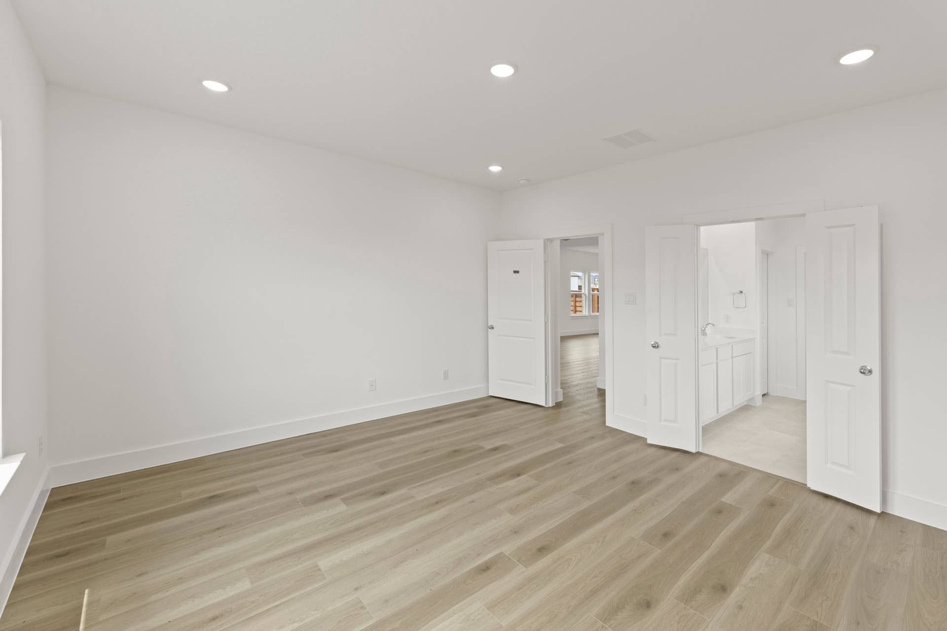 Spacious bedroom with wood flooring and en-suite bathroom access.