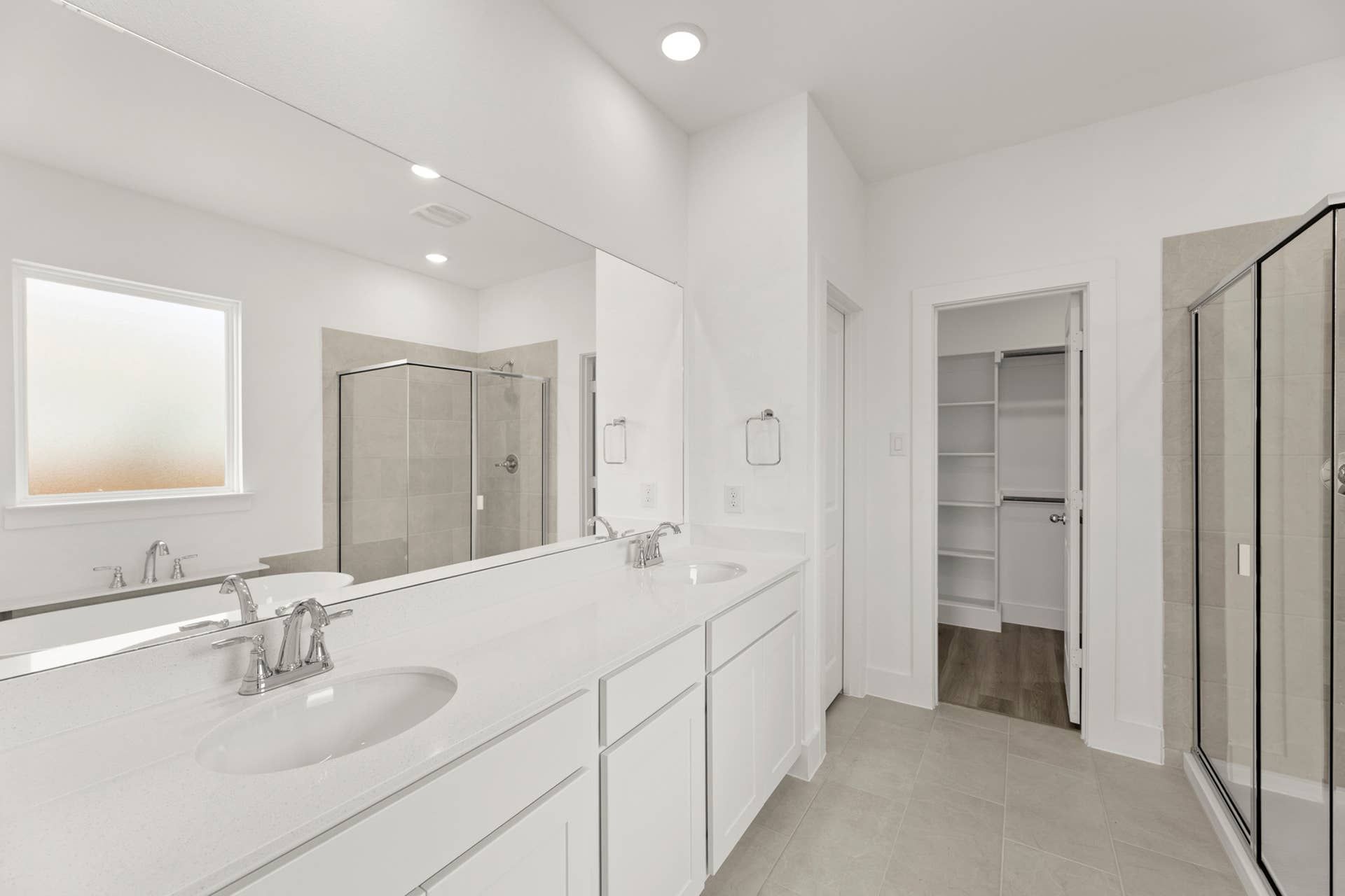 Spacious modern bathroom with double vanity and glass shower enclosure.