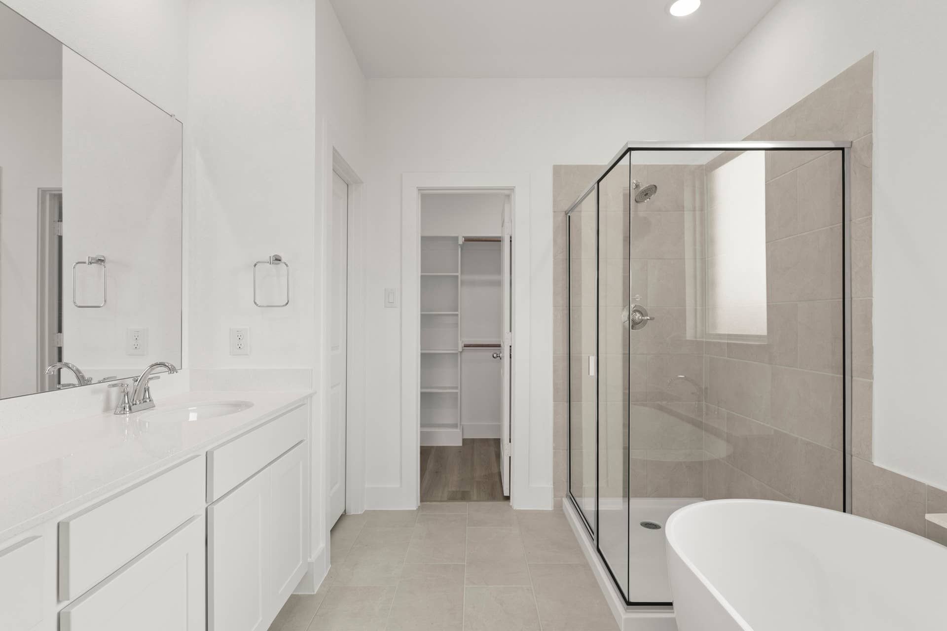 Modern bathroom with glass shower, white vanity, and freestanding tub.