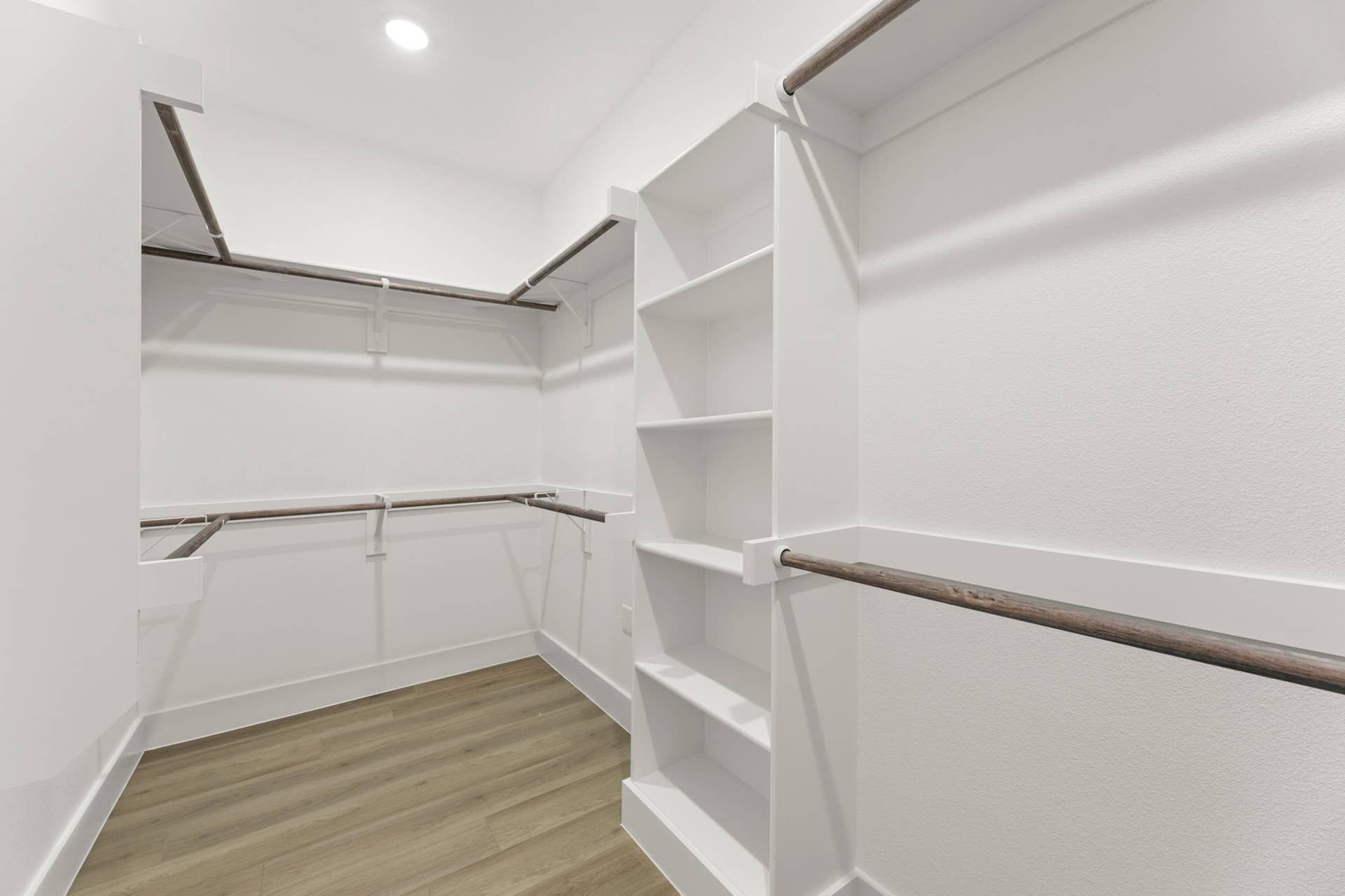 Spacious walk-in closet with shelving and hardwood floors.