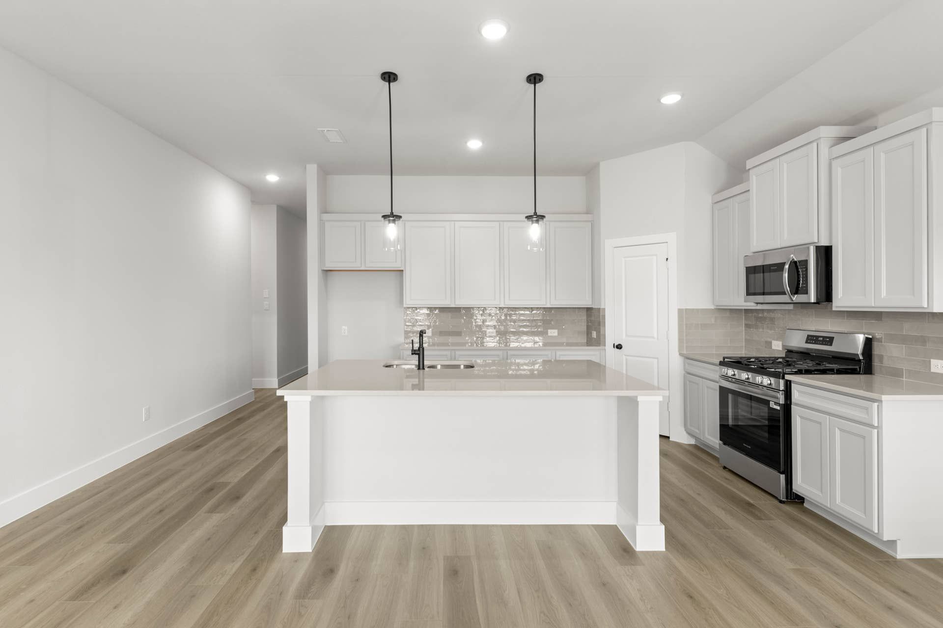 Modern kitchen with white cabinets, island, and stainless steel appliances.