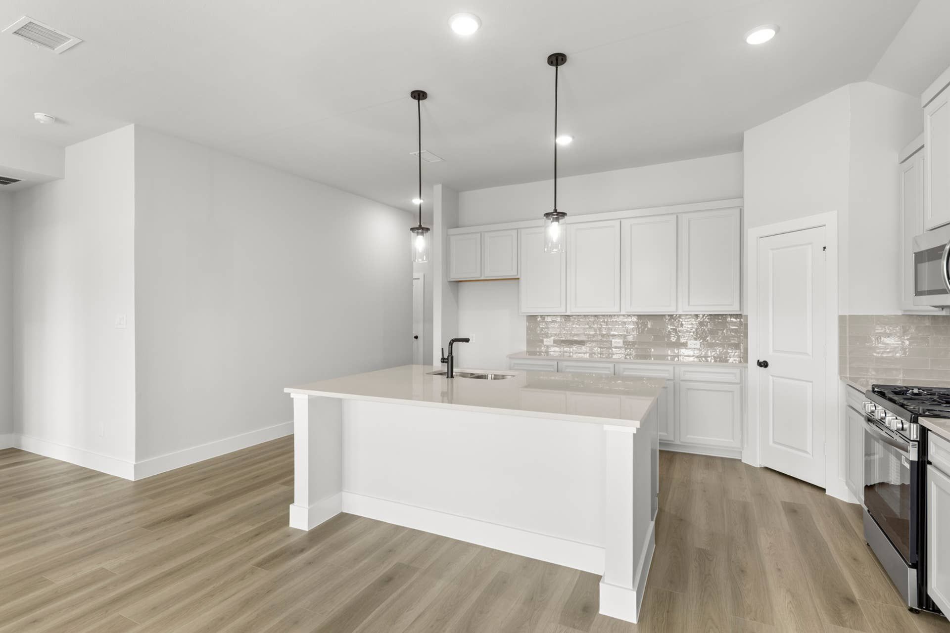 Modern kitchen with white cabinetry, island, and stainless steel appliances.