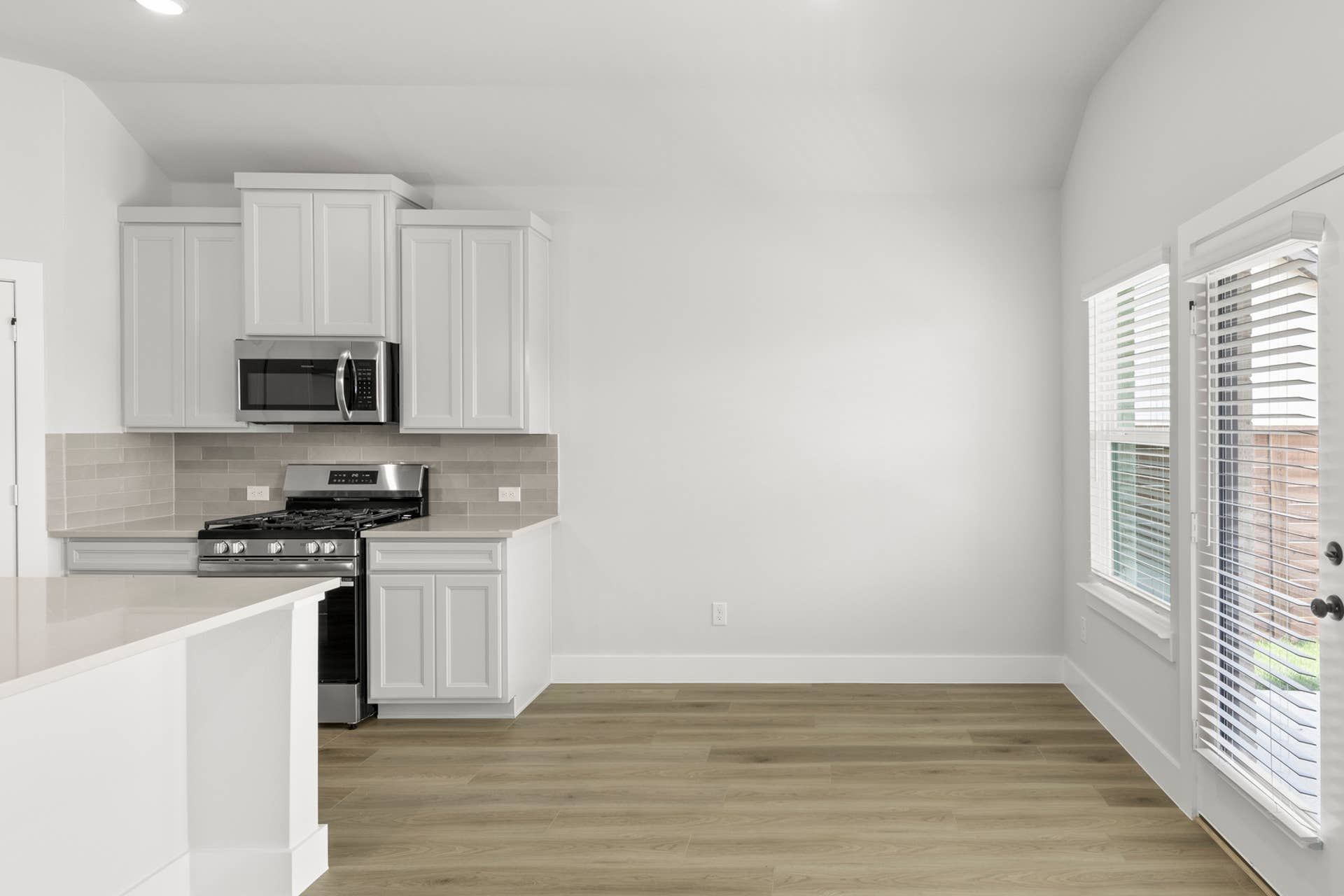 Modern kitchen with white cabinets, stainless steel appliances, and wooden flooring.