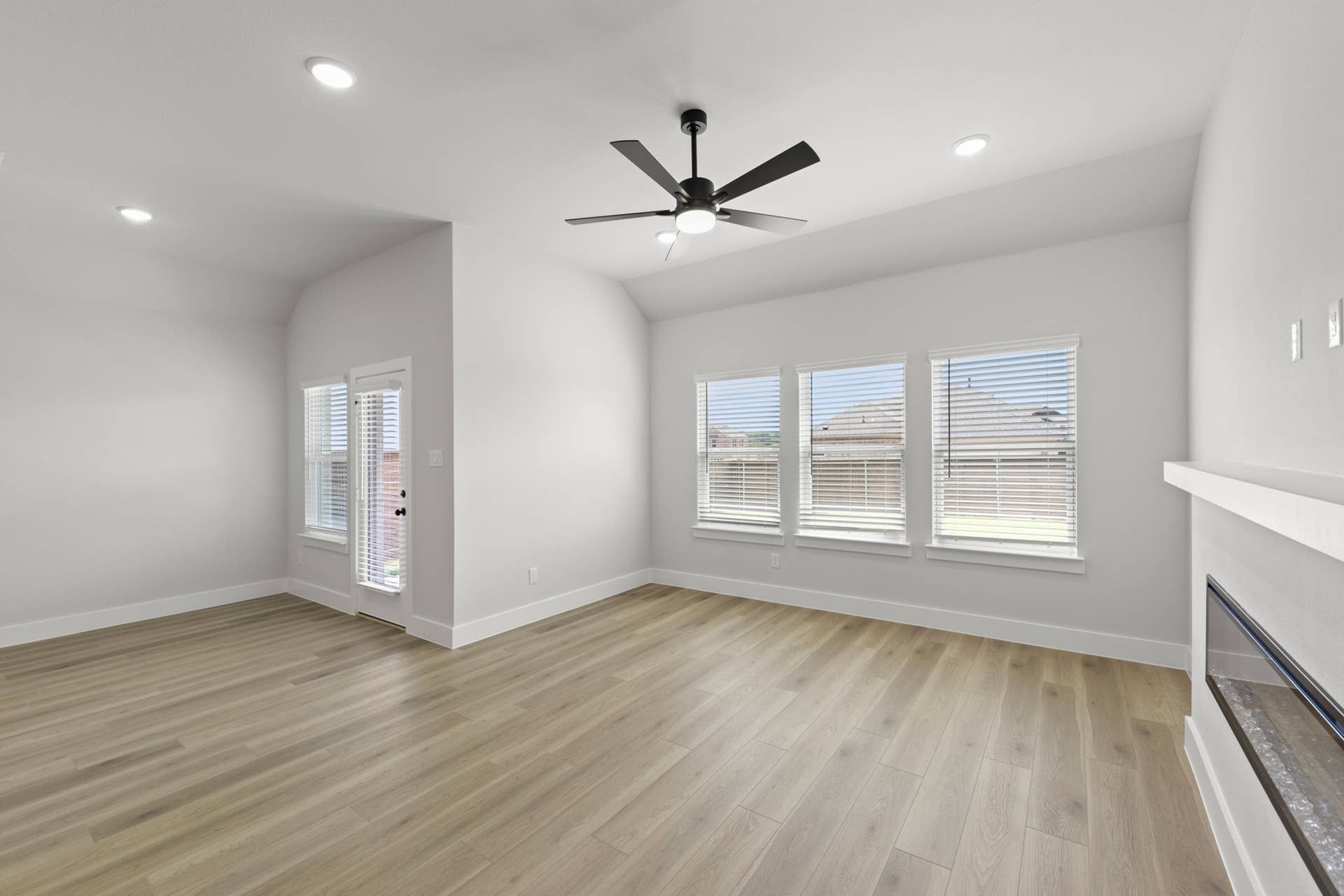 Spacious living room with wood floors, ceiling fan, and large windows.