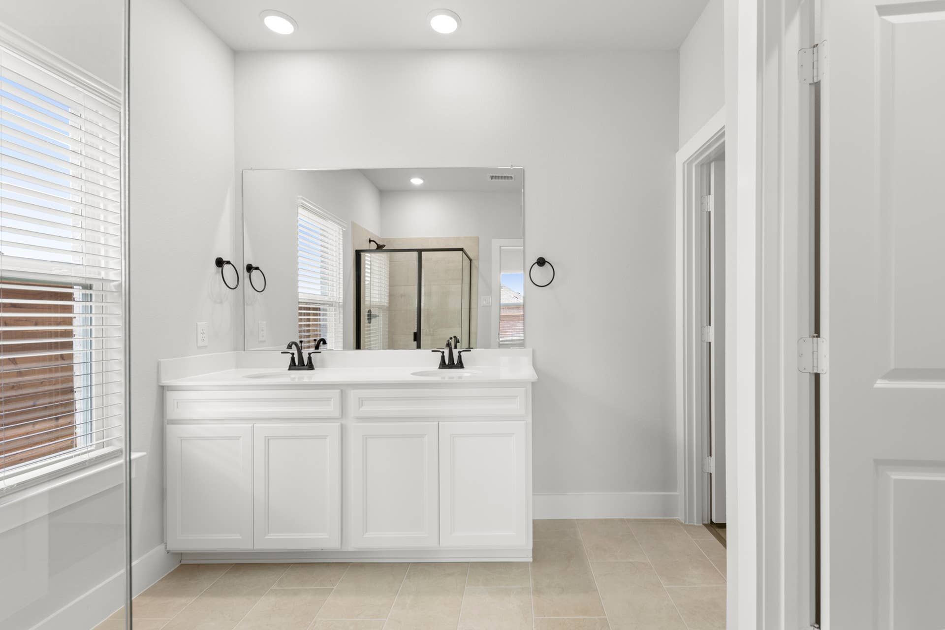 Modern bathroom with double vanity and glass-enclosed shower.
