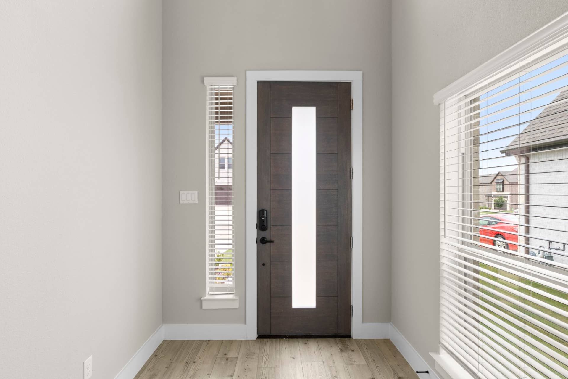Modern entryway with sleek wooden door and bright sidelights.