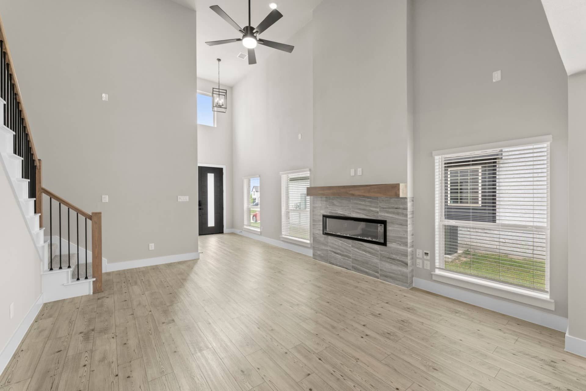 Spacious living room with high ceiling, modern fireplace, and wooden flooring.