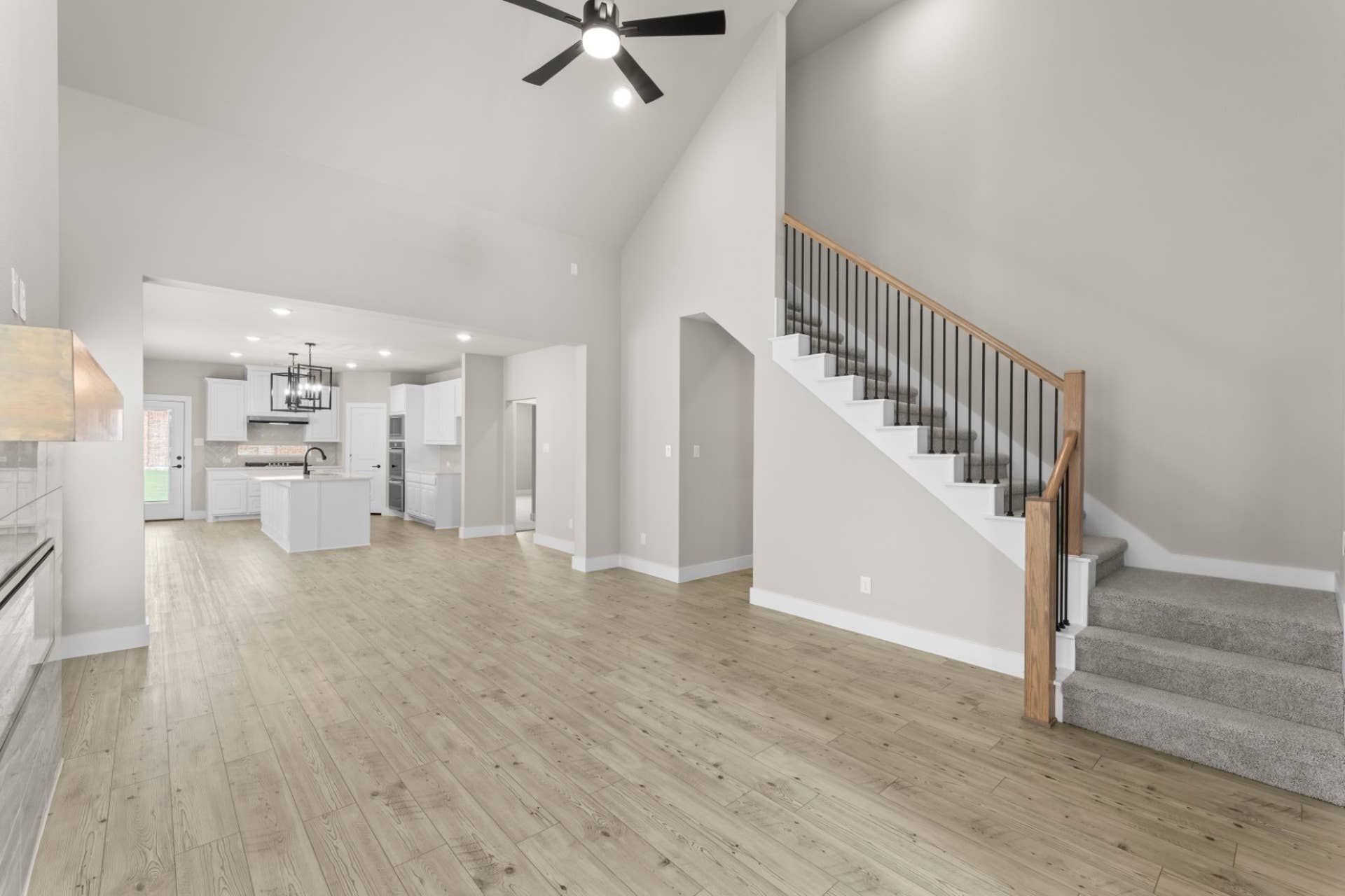 Spacious open-concept living area with modern kitchen and staircase.