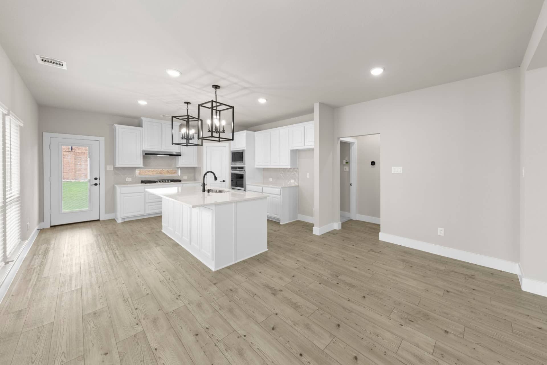 Spacious modern kitchen with island, white cabinetry, and pendant lighting.